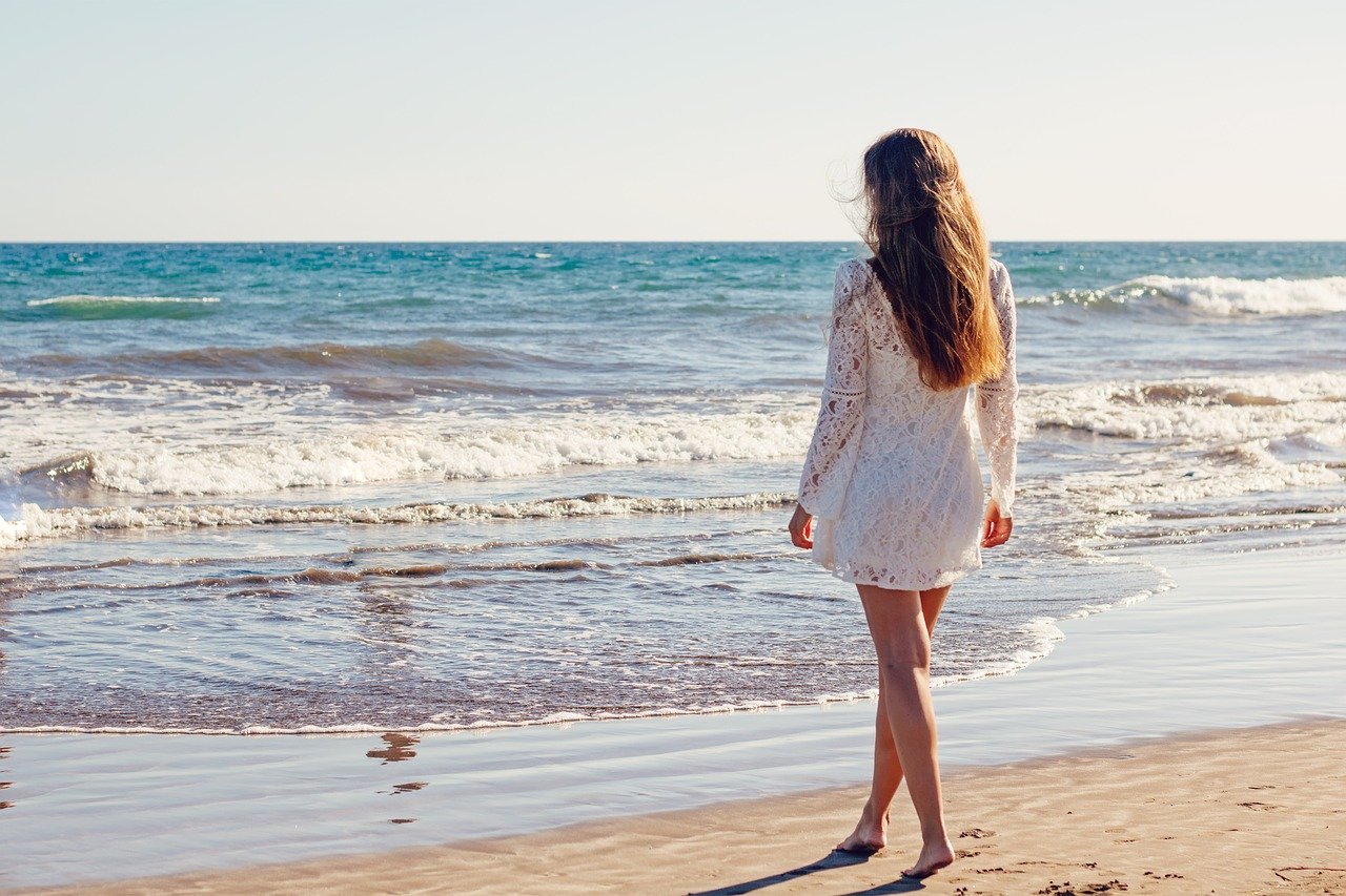 Une jeune femme aux cheveux longs à la plage. | Photo : Pixabay