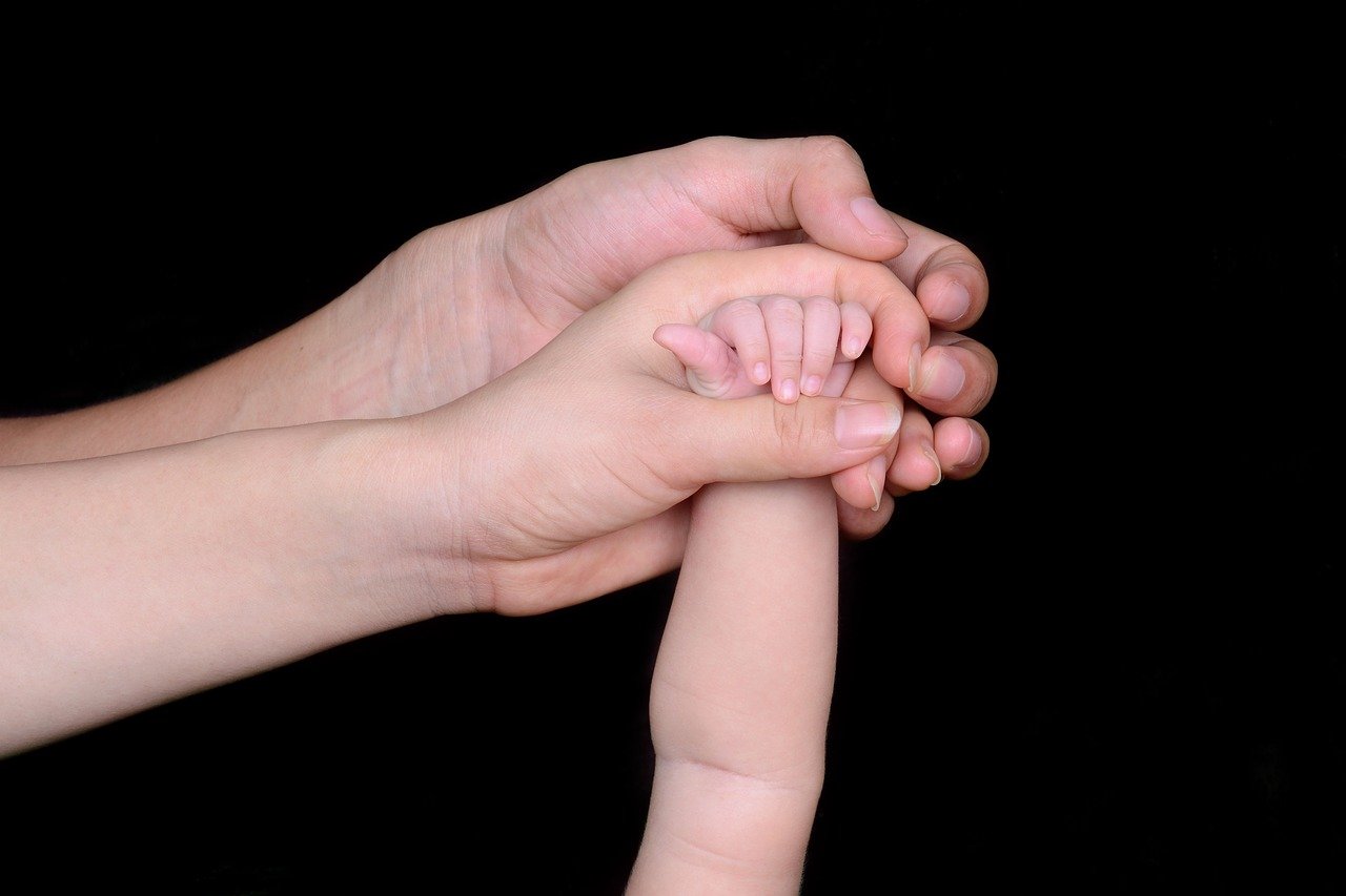 La main du bébé tenue par ses parents. Photo : Pixabay