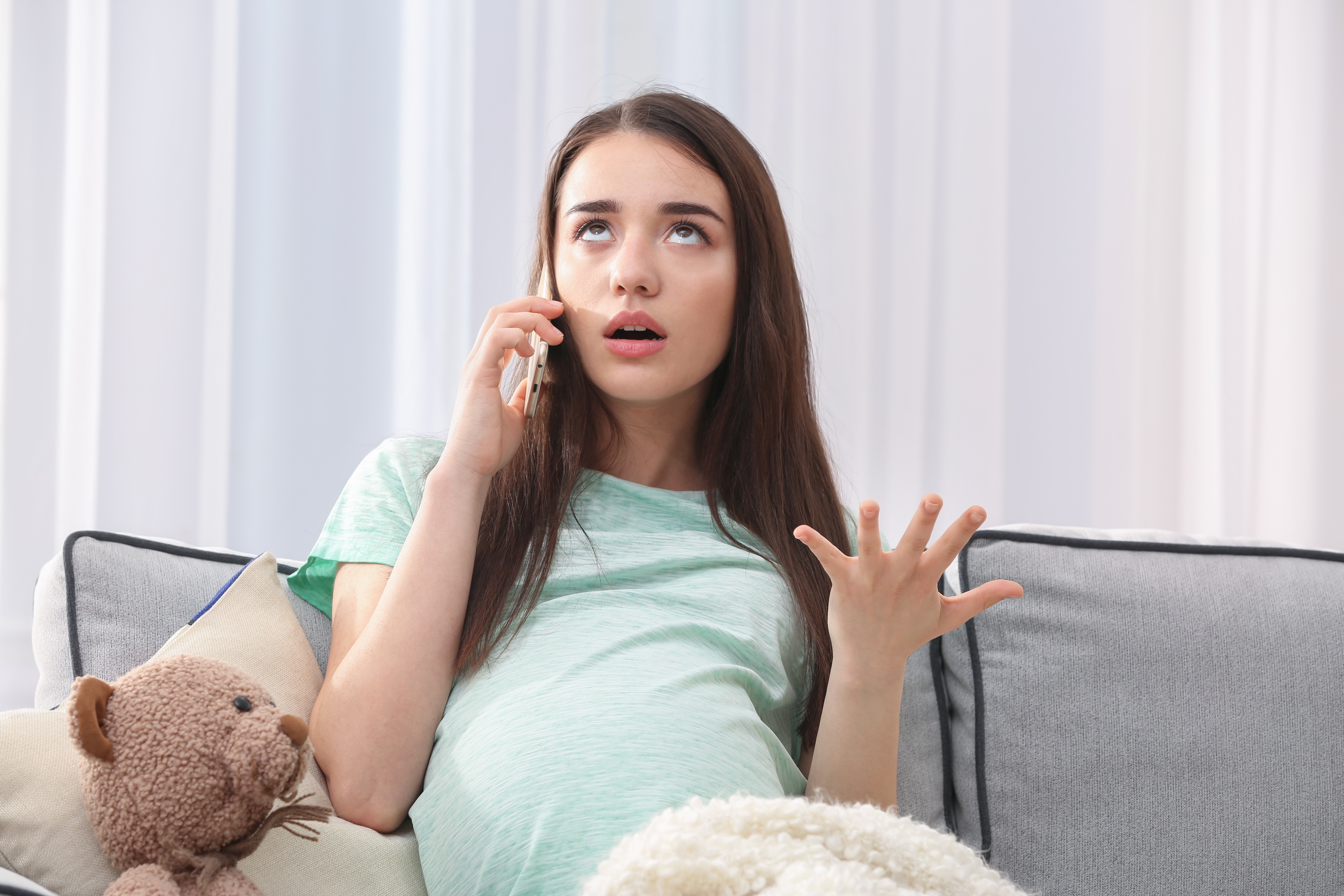 Une femme enceinte qui a l'air ennuyée alors qu'elle est au téléphone | Source : Shutterstock