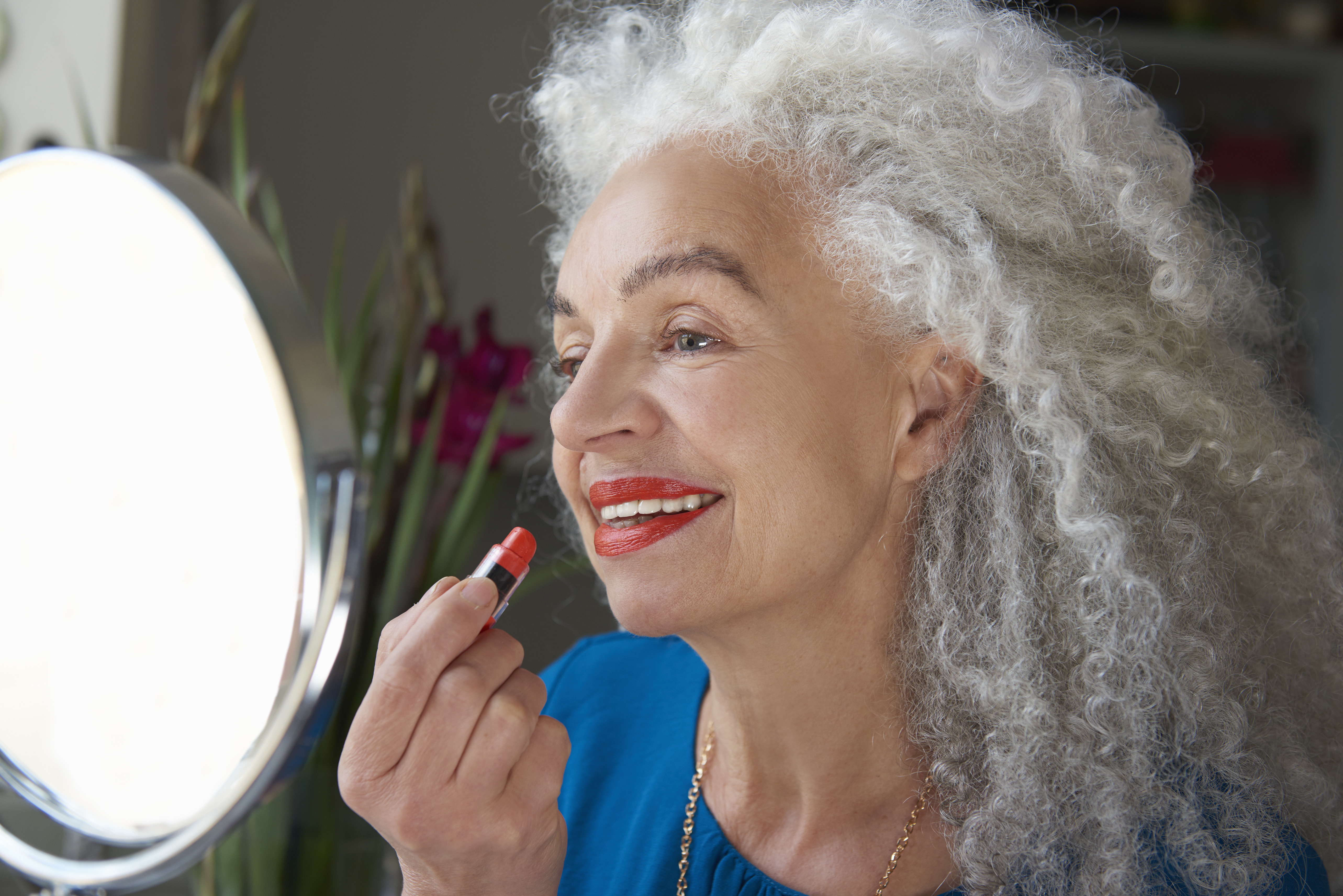 Une femme appliquant du rouge à lèvres rouge | Source : Getty Images