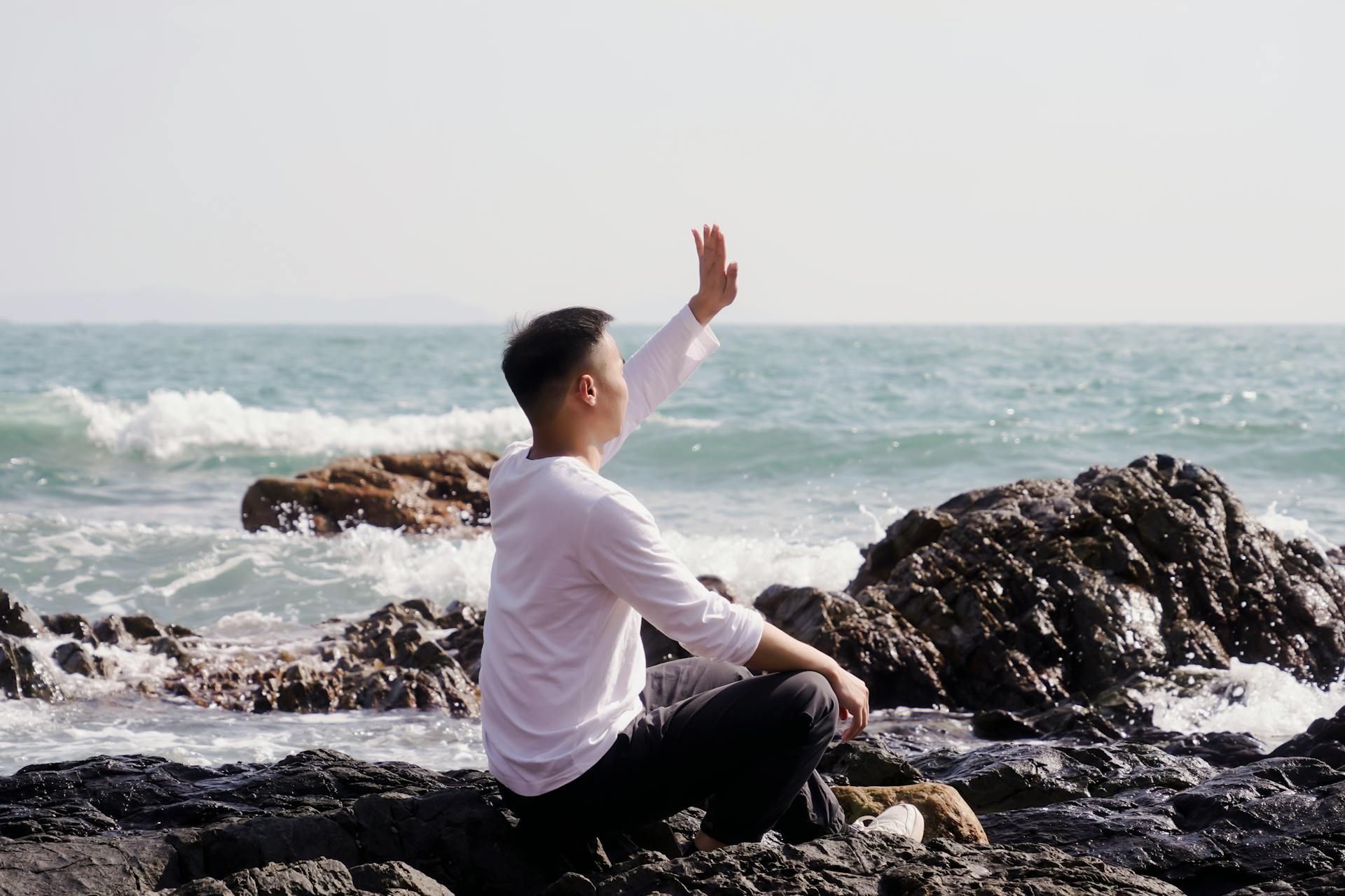 Un homme assis sur une plage rocheuse | Source : Pexels