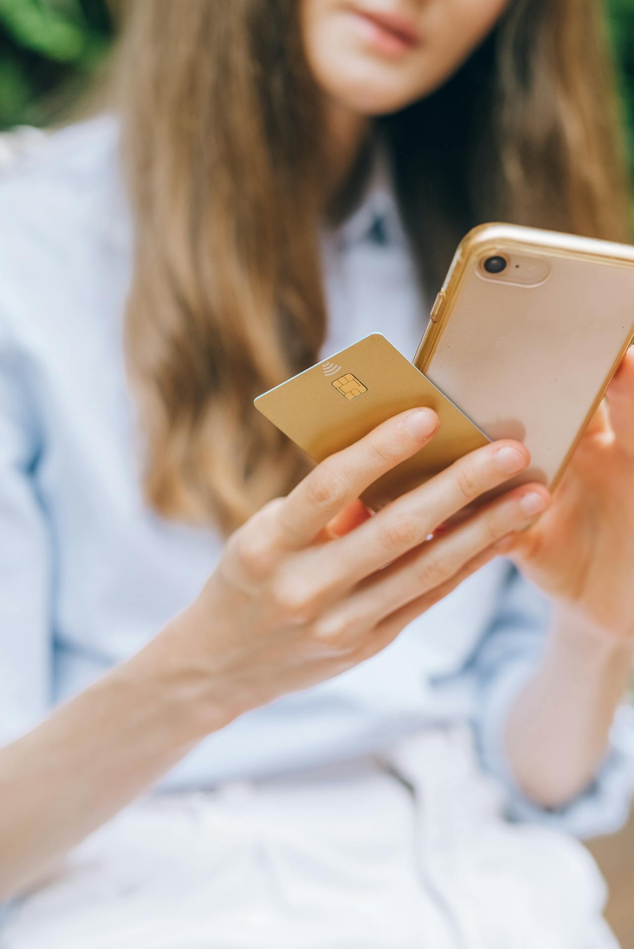 Une jeune femme tenant son téléphone et sa carte de crédit | Source : Pexels
