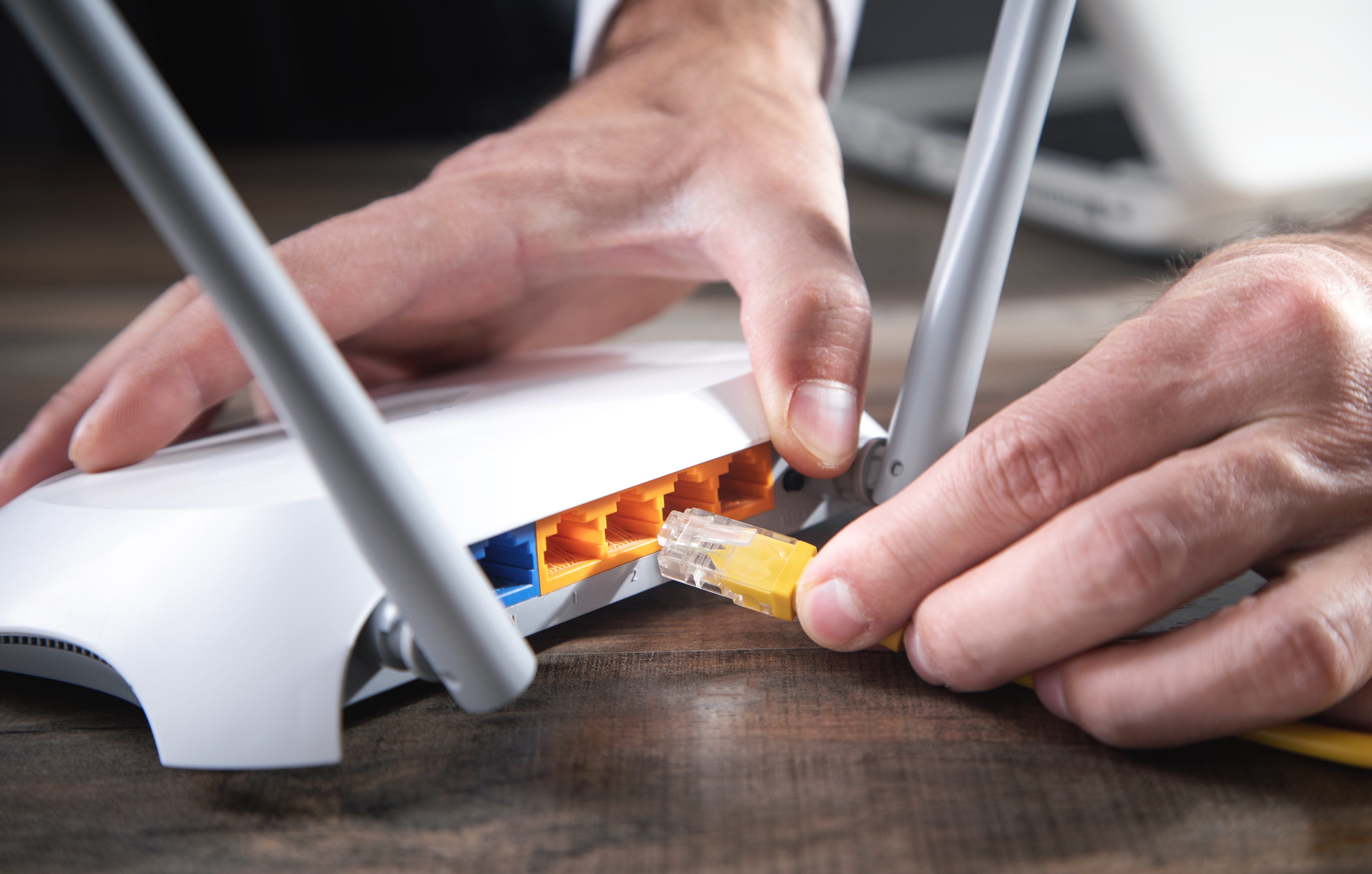 Un homme branchant un câble sur un routeur internet | Source : Shutterstock