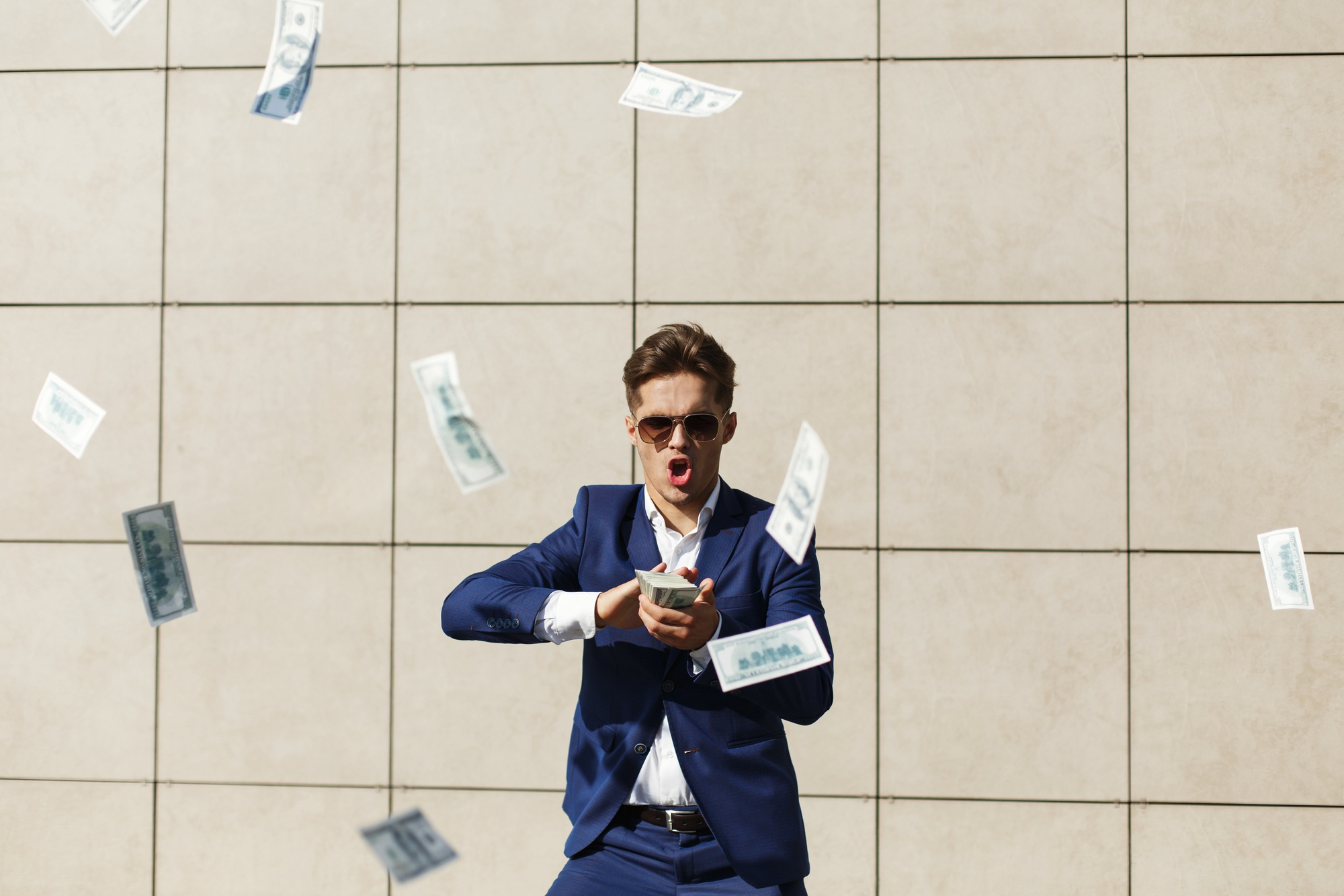 Un homme portant des lunettes de soleil et un costume tout en jetant de l'argent dans la rue | Source : Freepik