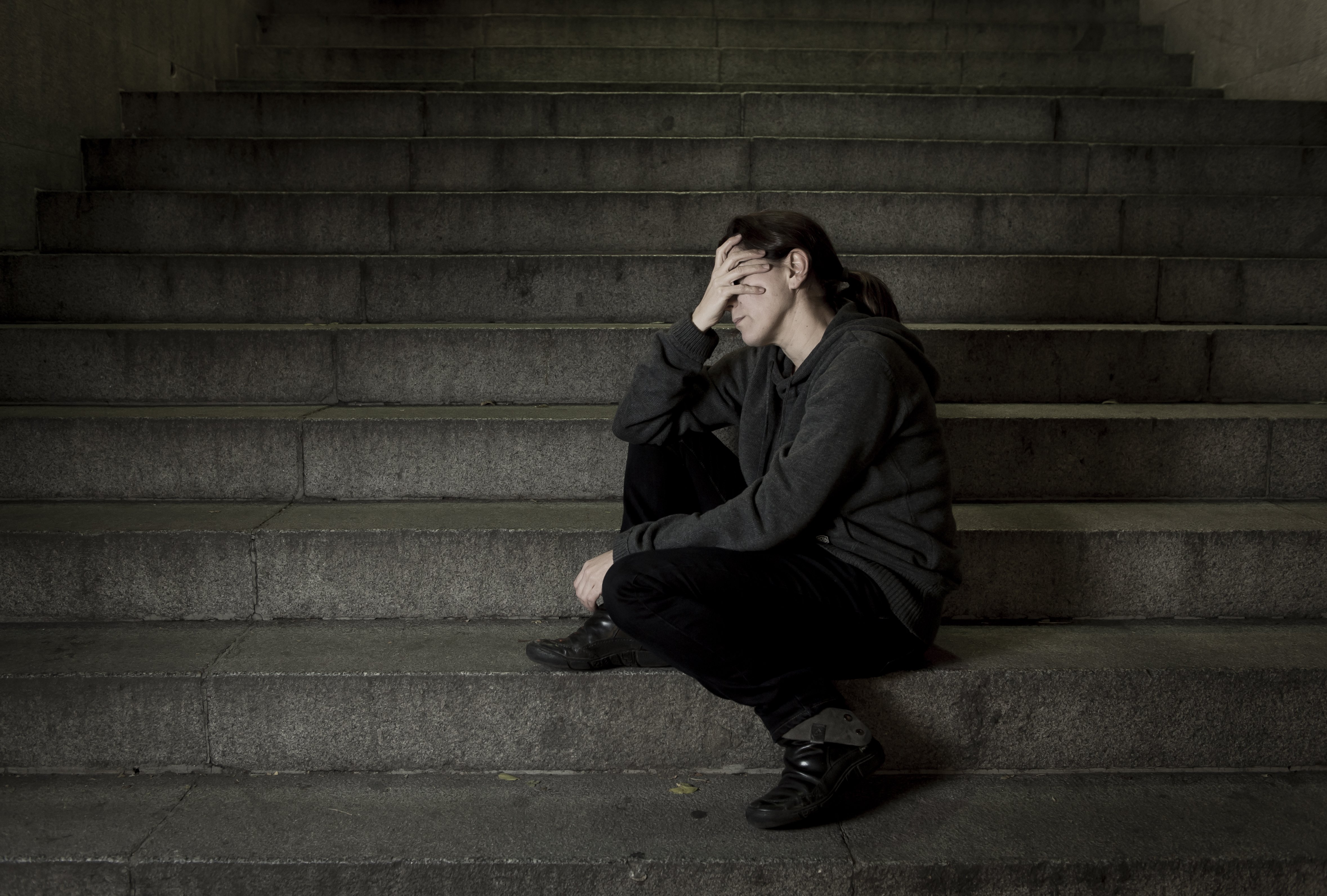 Une femme seule et triste dans l'escalier du métro de la rue | Photo : Shutterstock