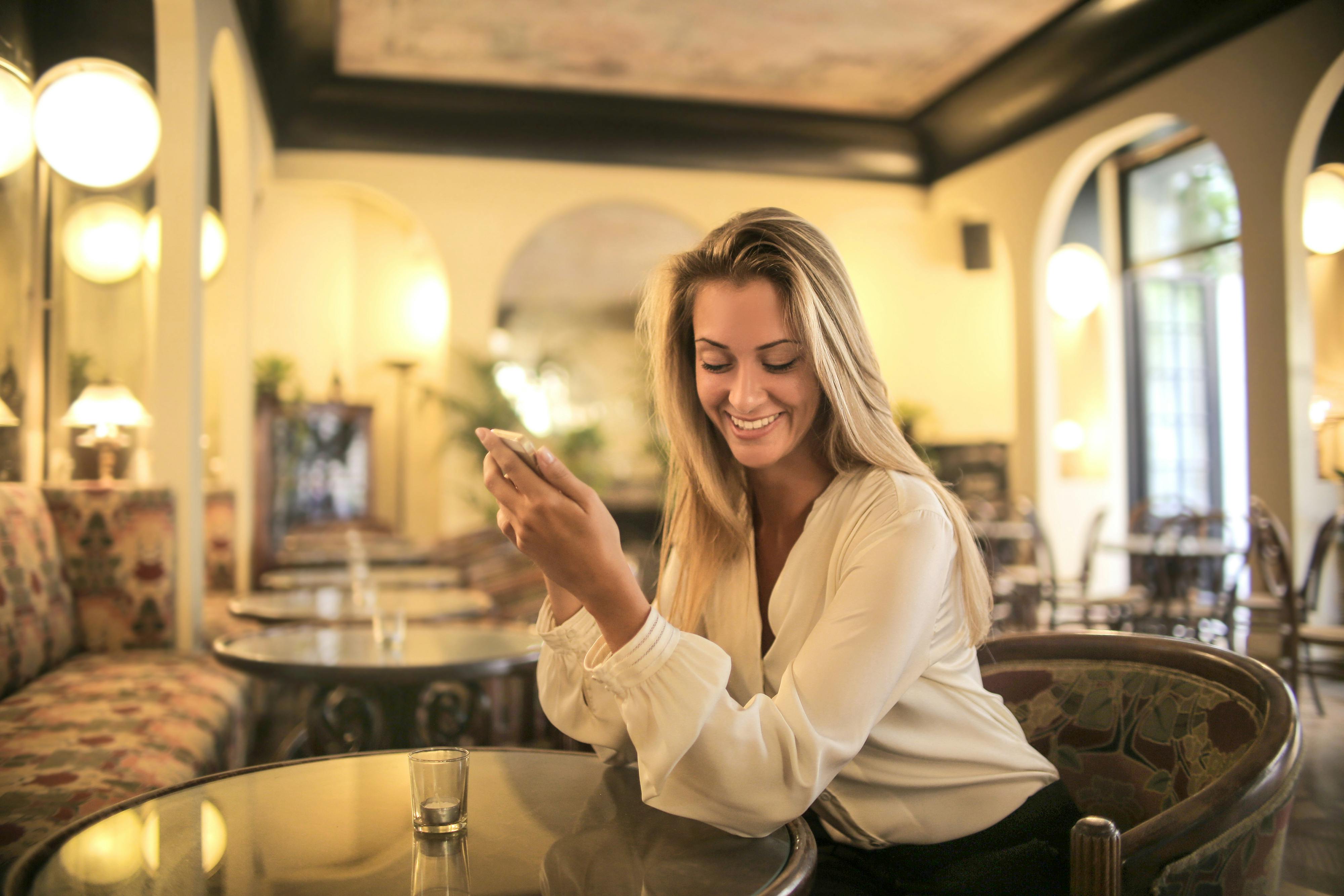 Une femme apparemment heureuse en brandissant son téléphone | Source : Pexels