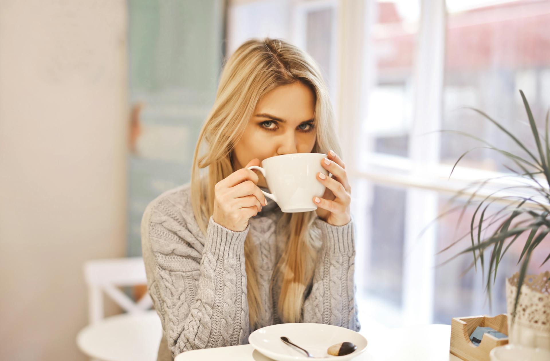 Une femme méfiante qui boit dans une tasse | Source : Pexels