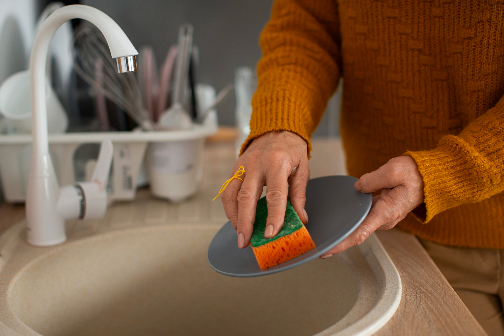 Une femme nettoie une assiette avec une éponge | Source : Freepik