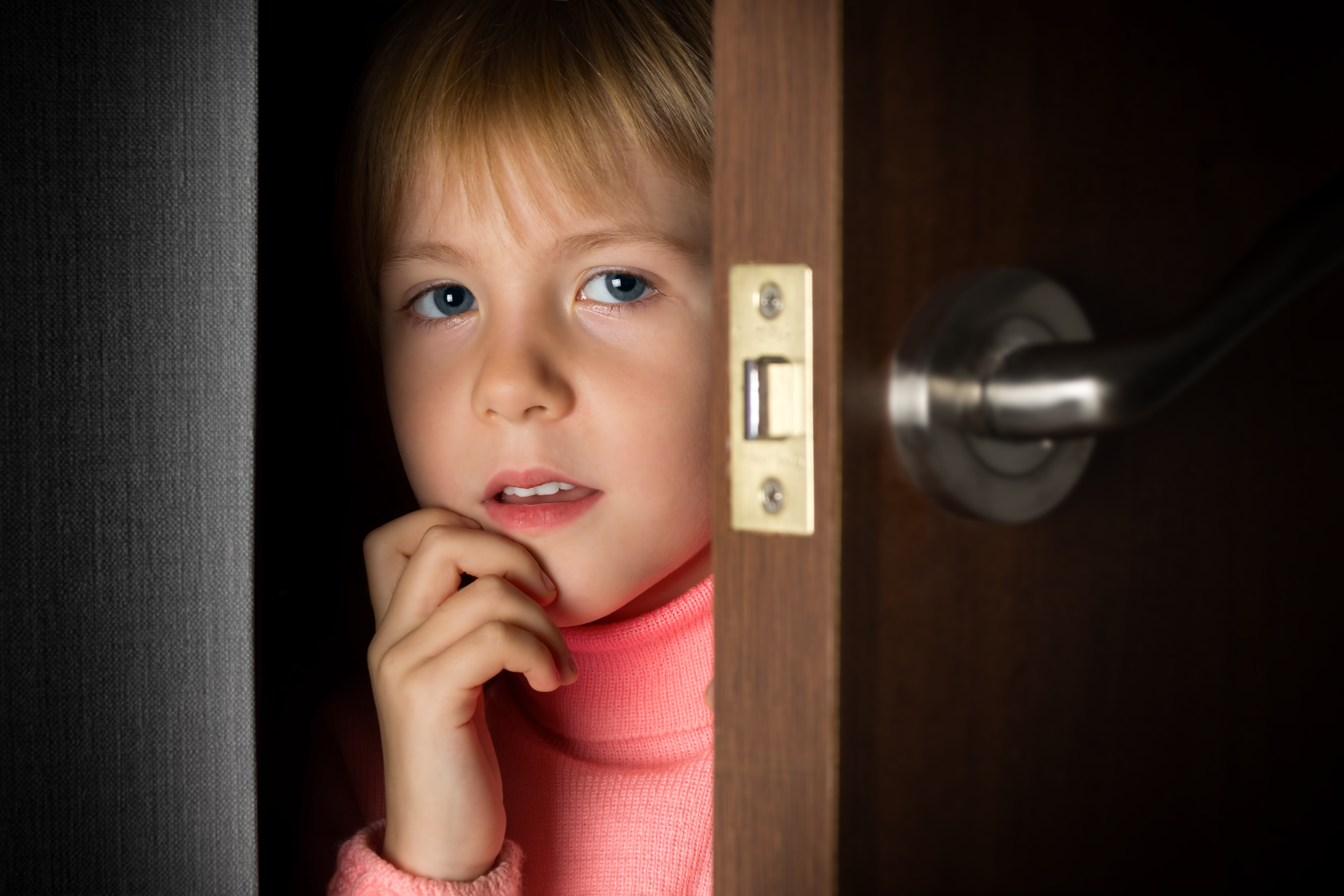 Une petite fille qui jette un coup d'œil à travers une porte | Source : Shutterstock