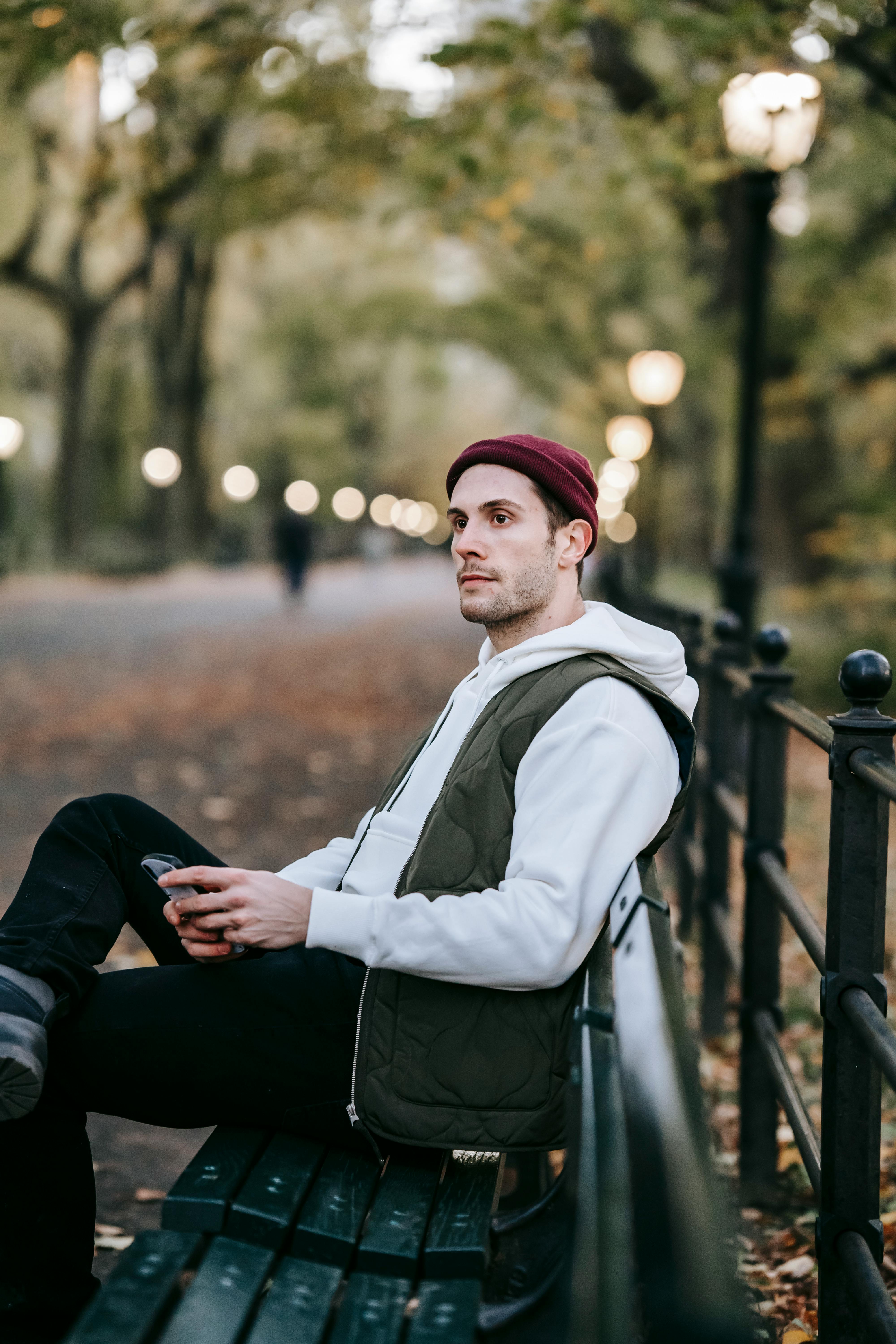 Un homme assis sur un banc contemplant quelque chose qu'il a vu sur son téléphone | Source : Pexels