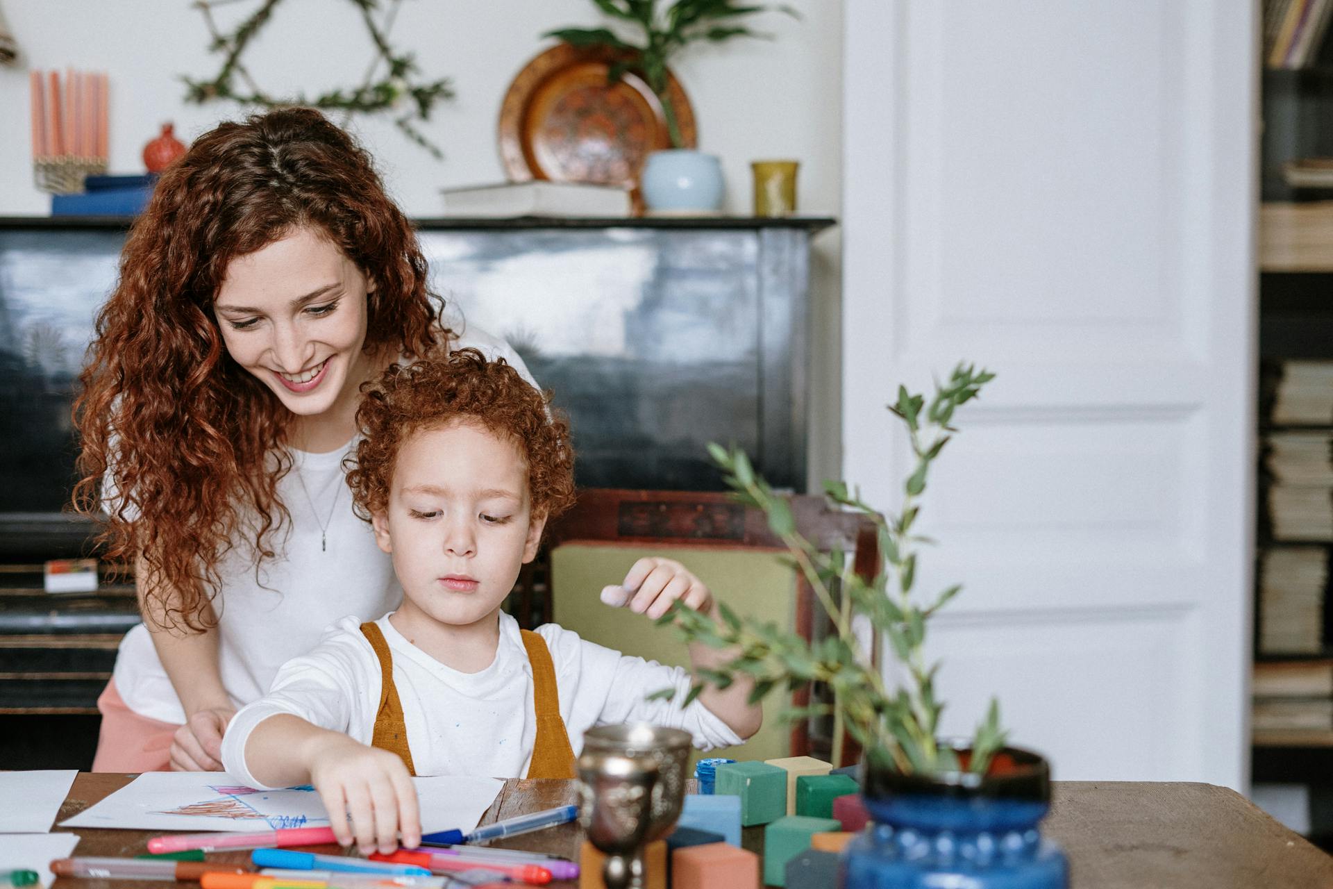 Une femme qui regarde son enfant dessiner | Source : Pexels