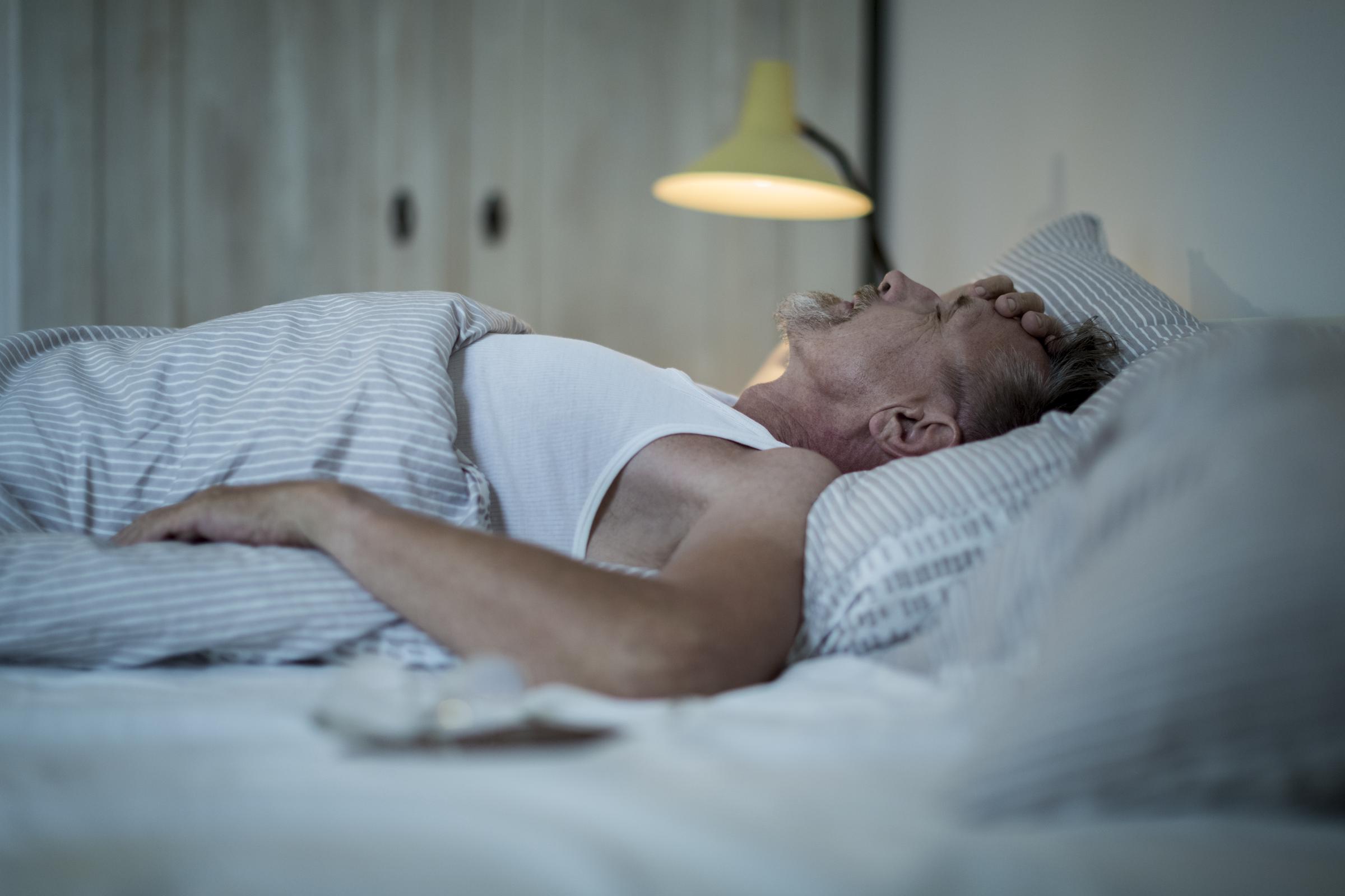 Homme allongé dans son lit la nuit, se sentant mal et incapable de dormir | Source : Getty Images