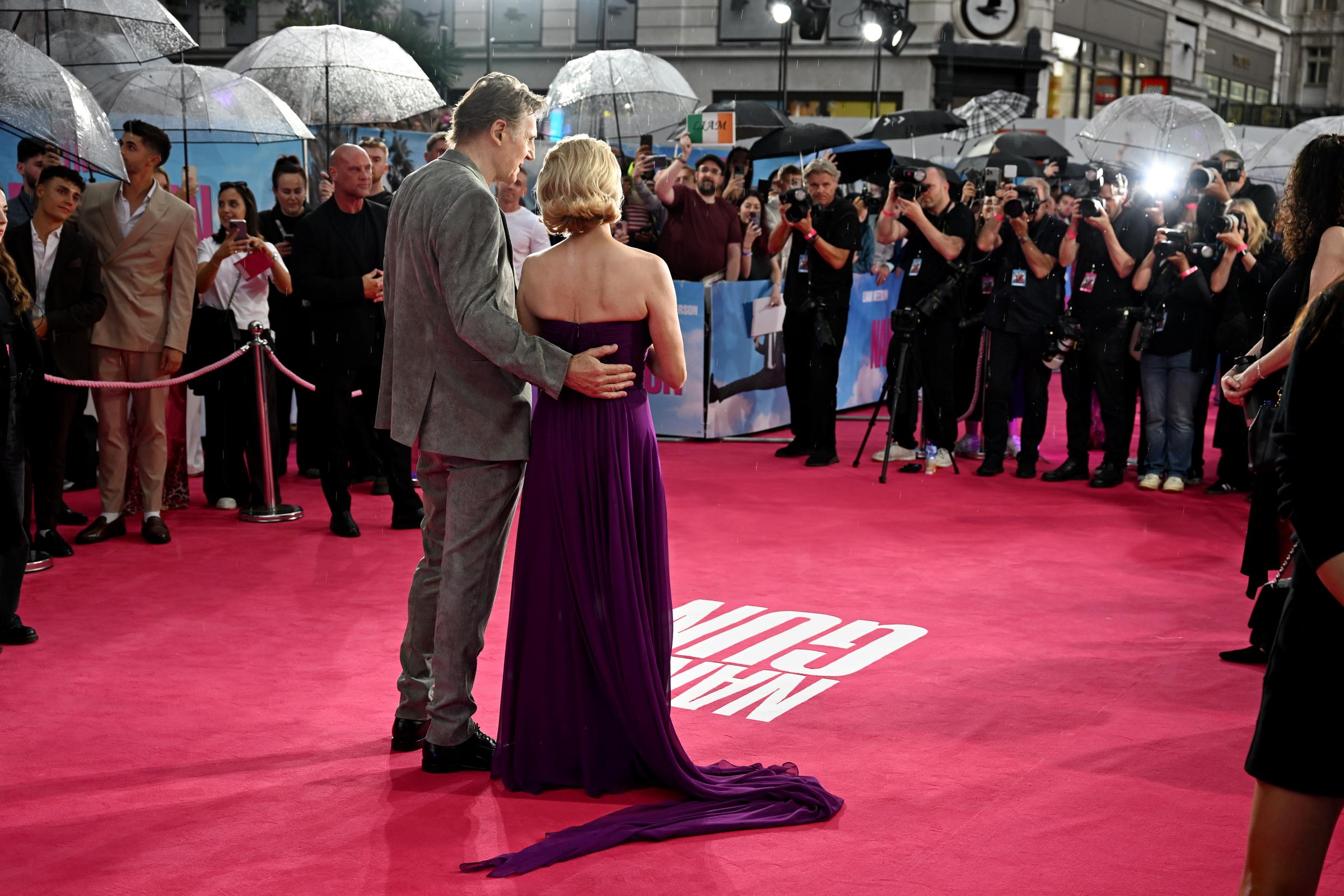 Liam Neeson tient la taille de Pamela Anderson alors que le couple prend des photos lors de la première britannique de « Y a-t-il un flic pour sauver le monde ? » au Cineworld Leicester Square à Londres, en Angleterre, le 22 juillet 2025 | Source : Getty Images