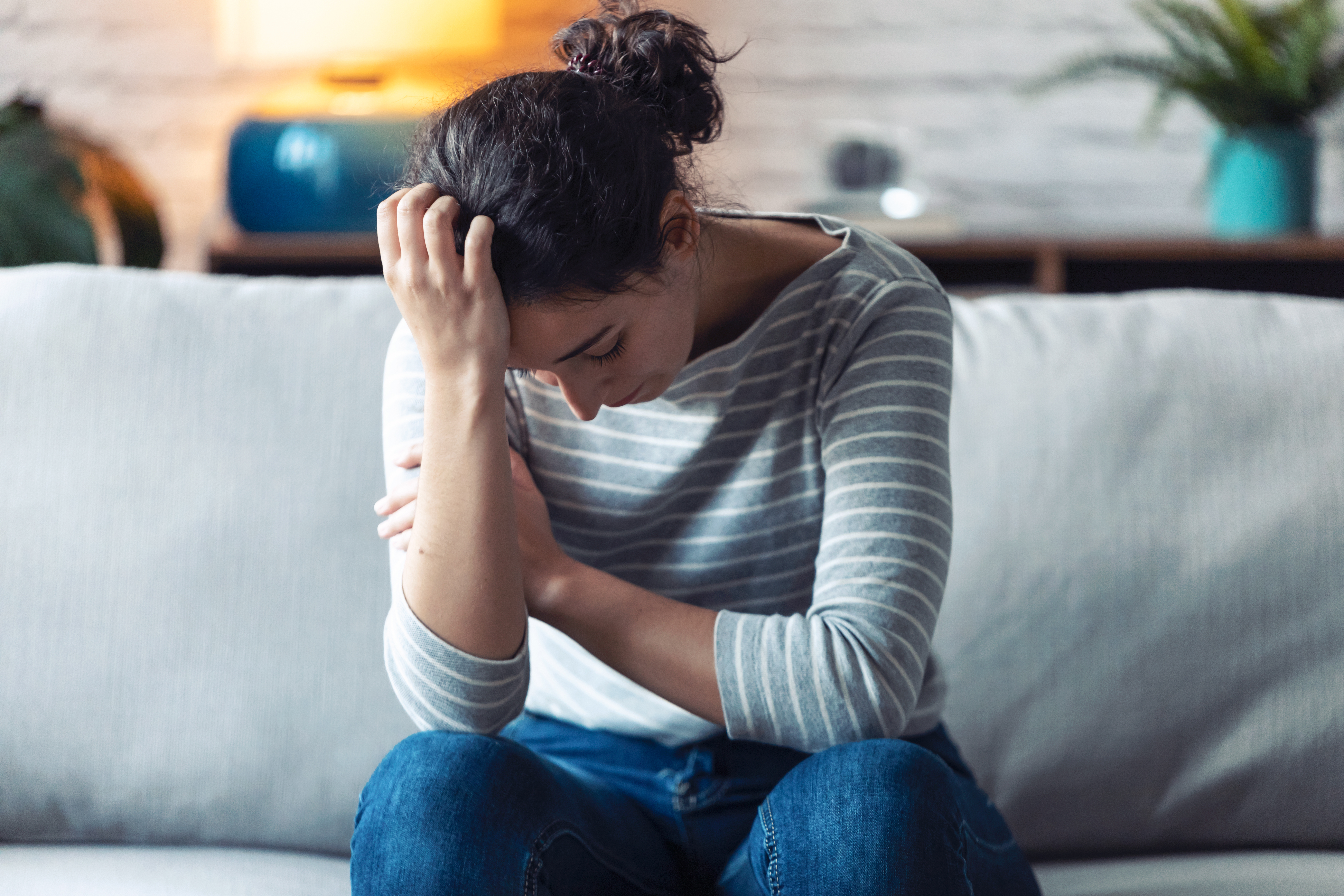 Une femme assise sur le canapé, l'air triste | Source : Shutterstock