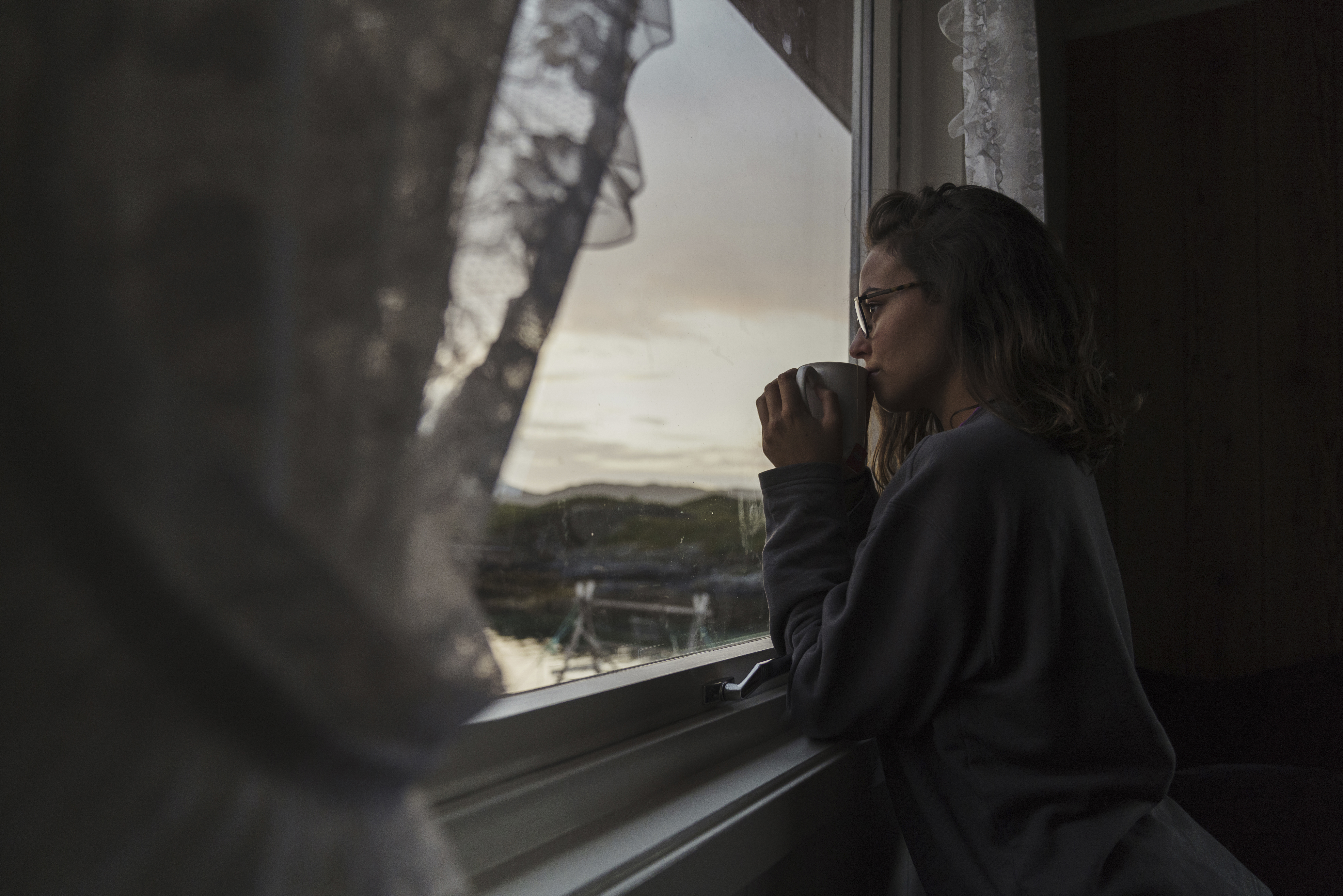 Une femme qui regarde par la fenêtre en buvant du thé | Source : Getty Images