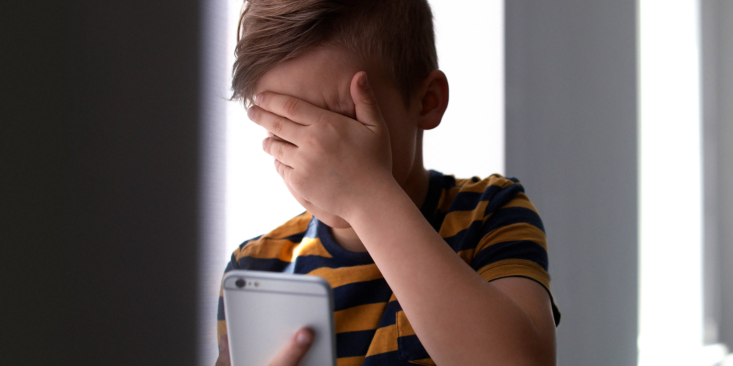 Garçon qui pleure en passant un appel | Source : Shutterstock