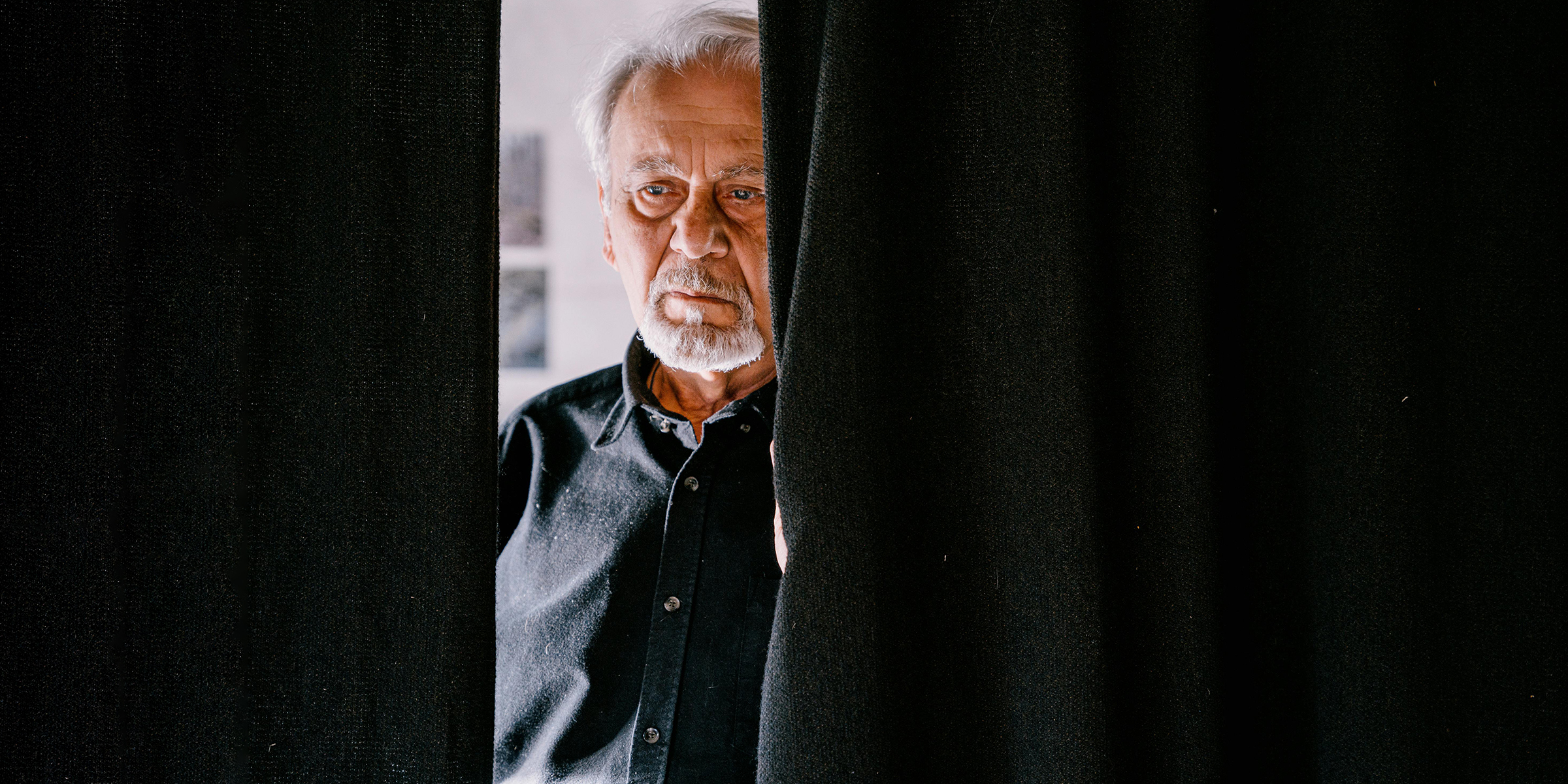 Homme triste se tenant derrière le rideau | Source : Pexels