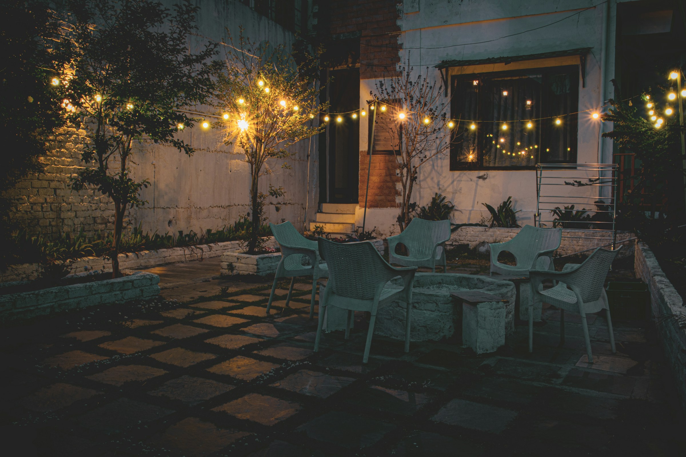 Vue lointaine d'un patio avec des lumières jaunes, des tables et des chaises | Source : Unsplash