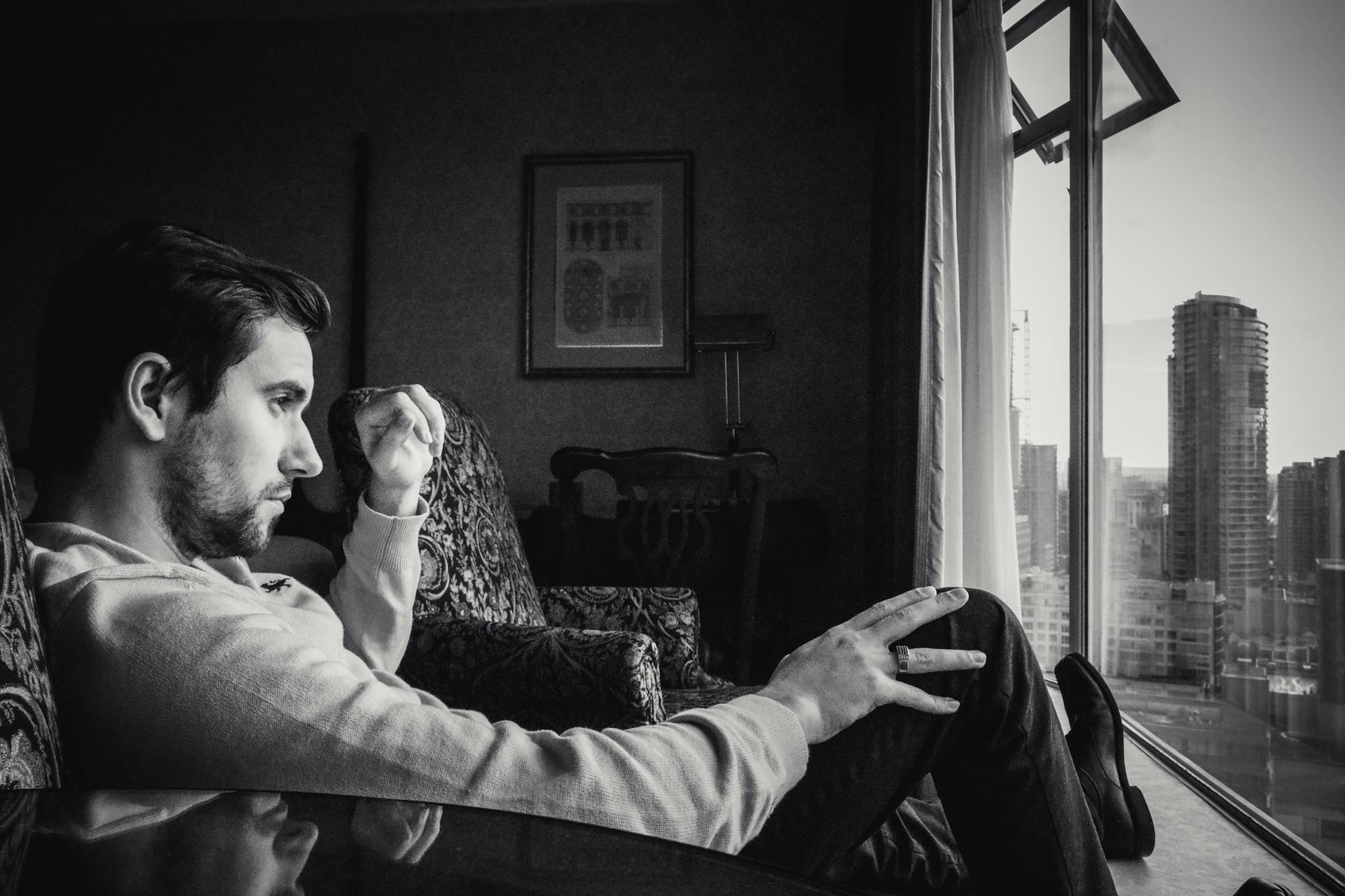 Une photo en niveaux de gris d'un homme qui regarde par la fenêtre | Source : Pexels