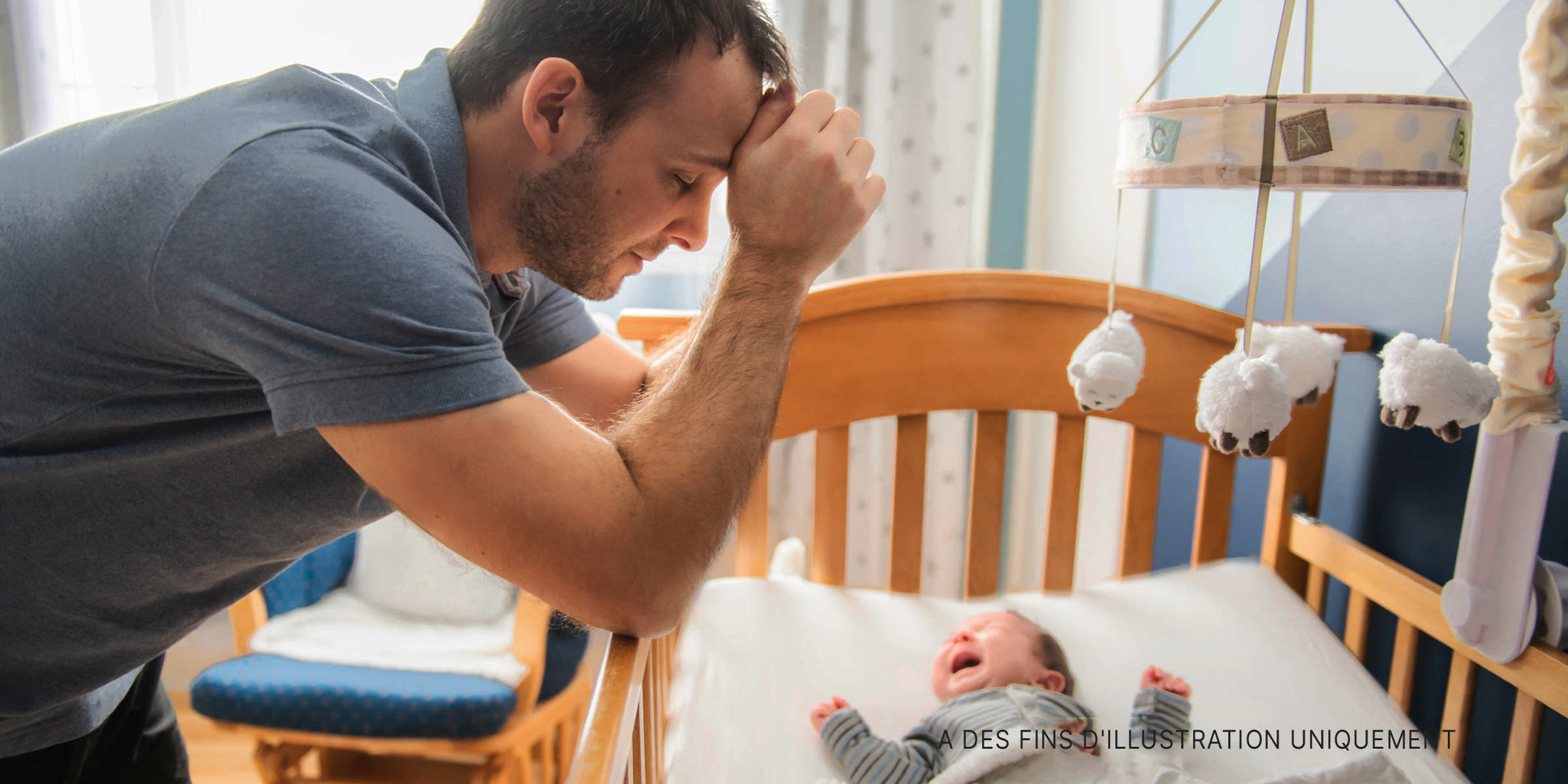 Homme regardant un bébé dans un berceau. | Source : Shutterstock