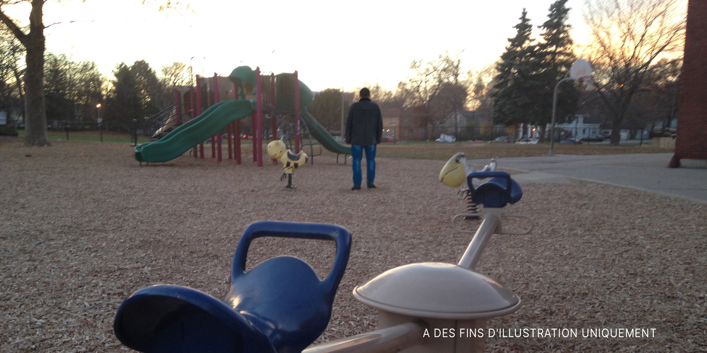 Un homme debout à côté d'un toboggan dans un parc. | Source : Shutterstock