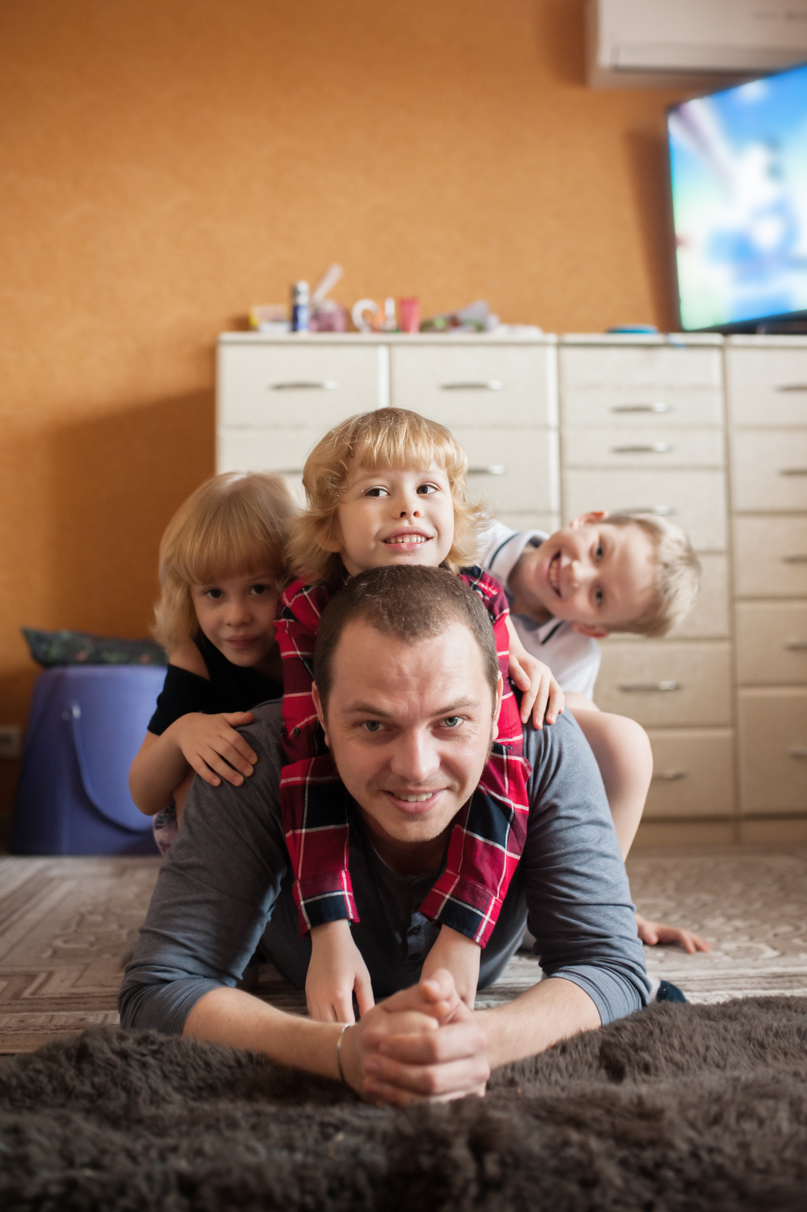 Un père allongé sur le sol avec ses enfants montés sur son dos | Source : Shutterstock