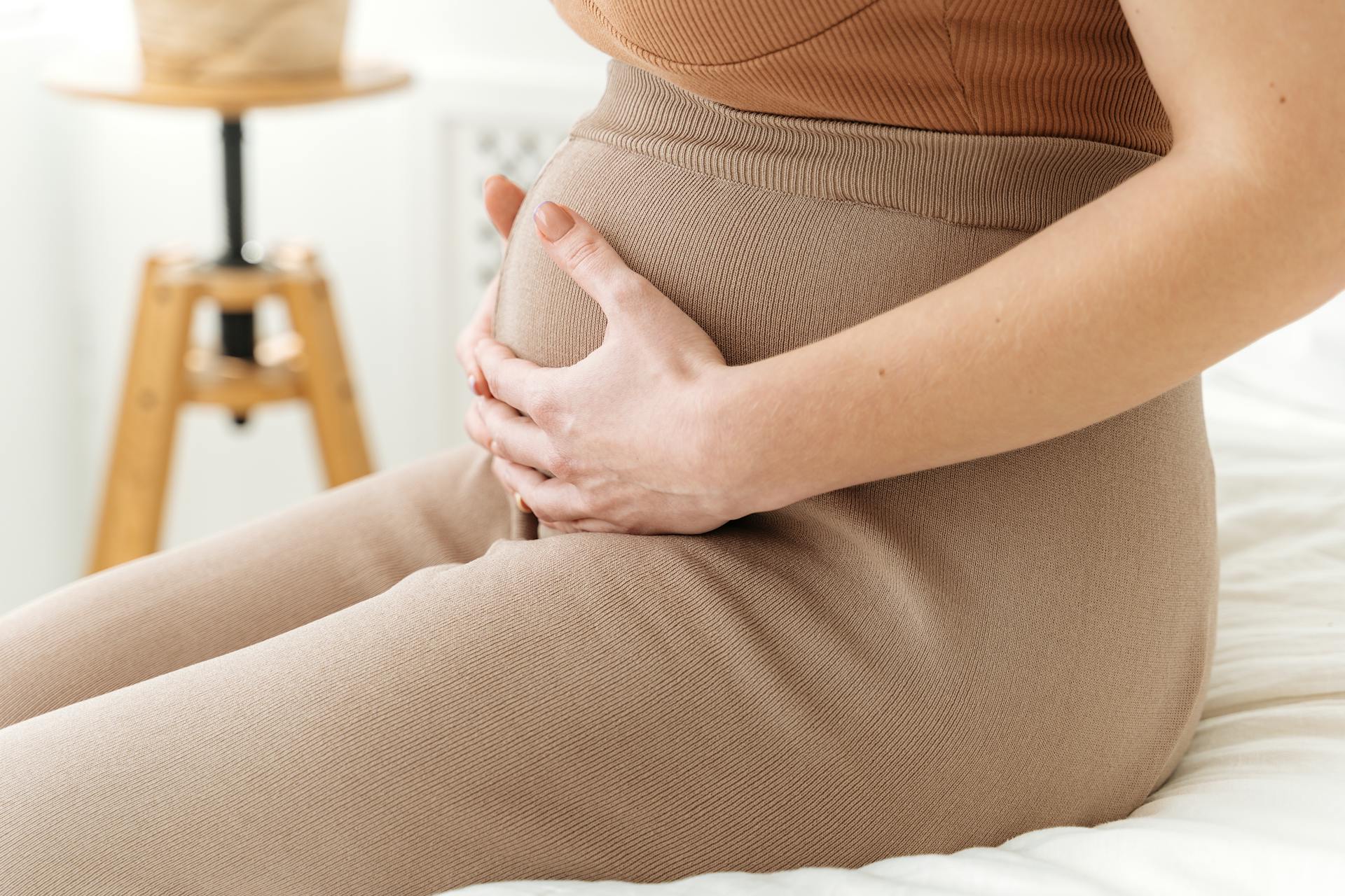 Une femme assise avec les mains sur son baby bump | Source : Pexels