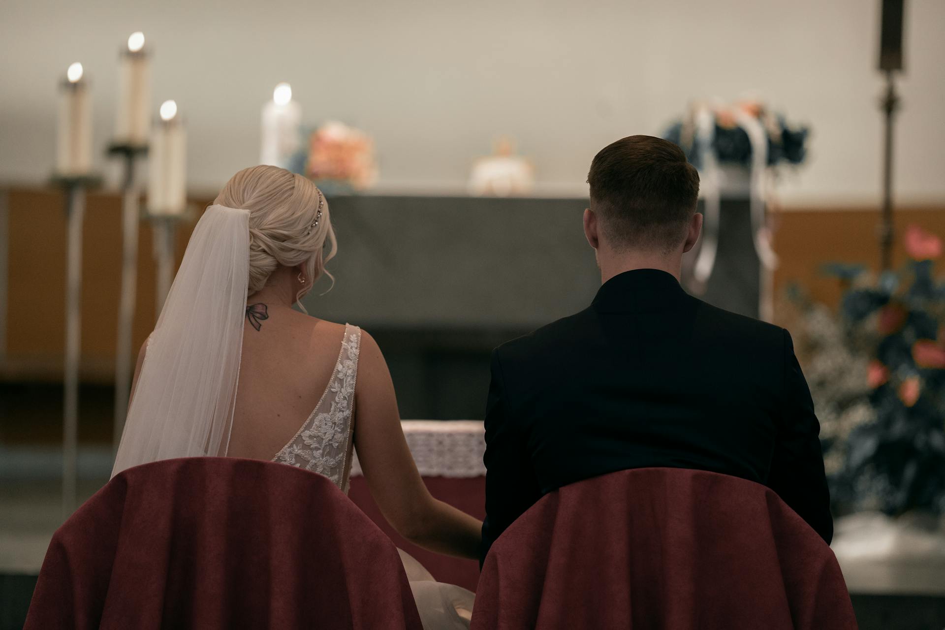 Vue arrière d'une mariée et d'un marié assis devant l'autel | Source : Pexels