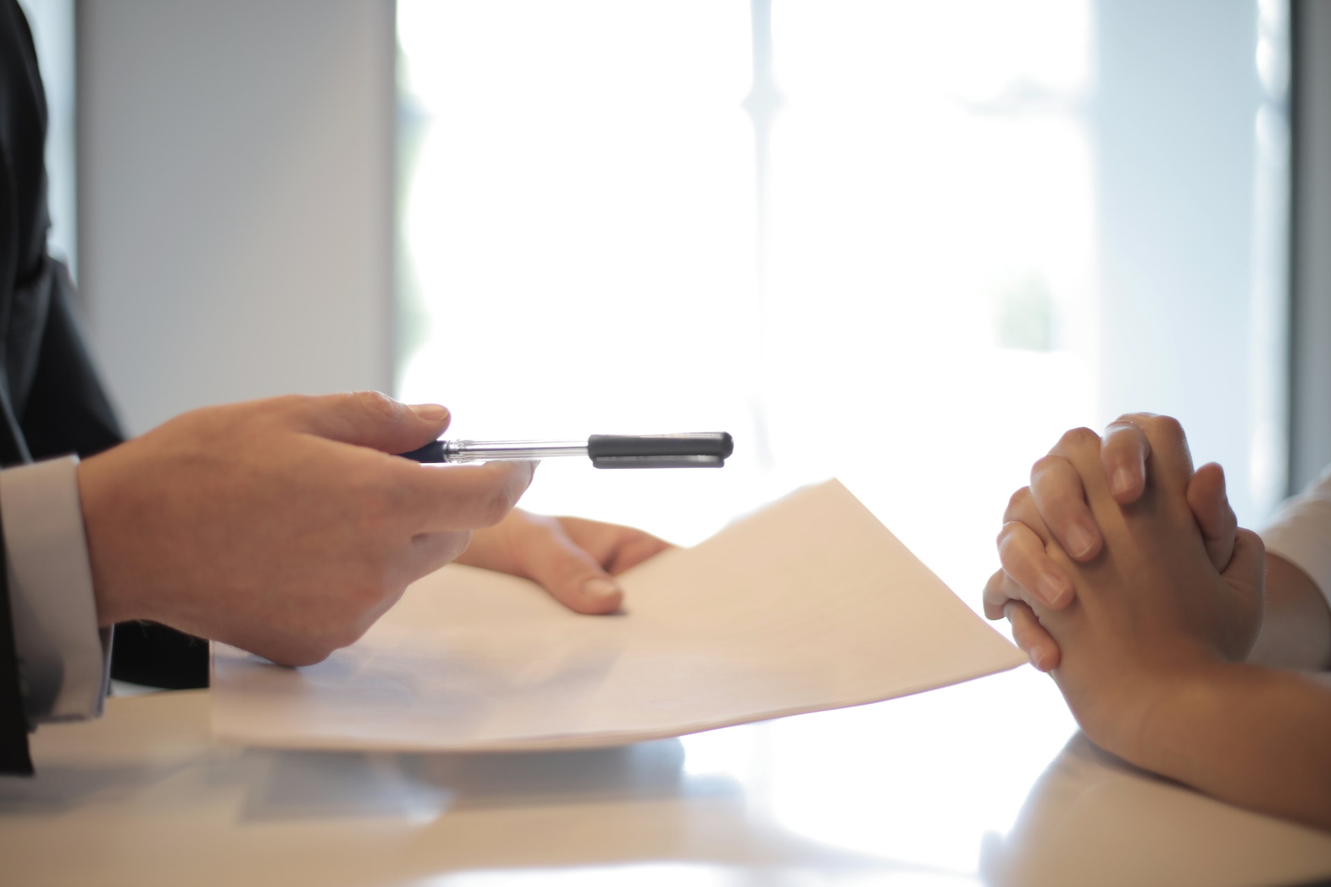 Un homme remettant un stylo et un papier à une femme | Source : Pexels