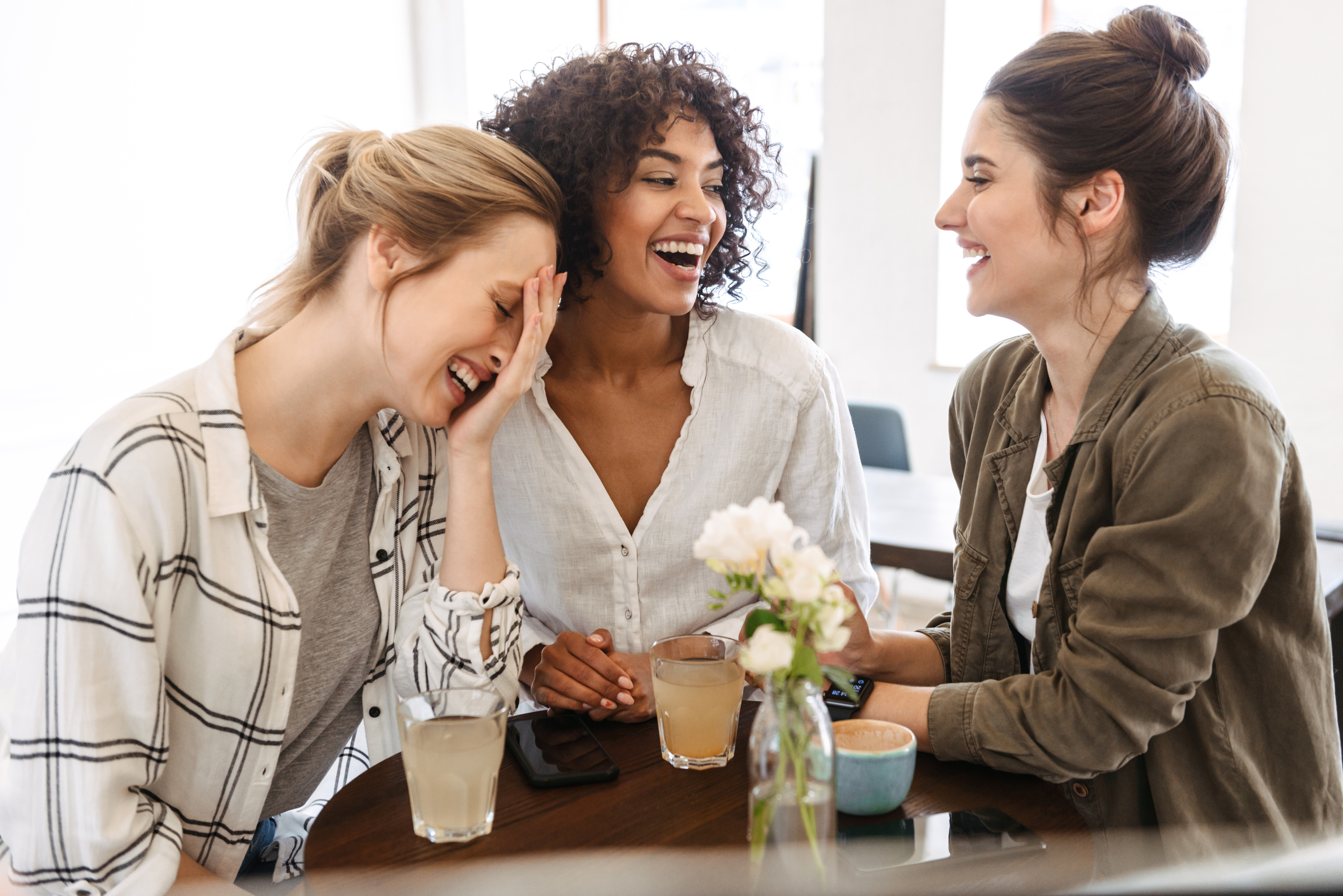 Trois femmes heureuses dégustant un café et des boissons | Source : Shutterstock