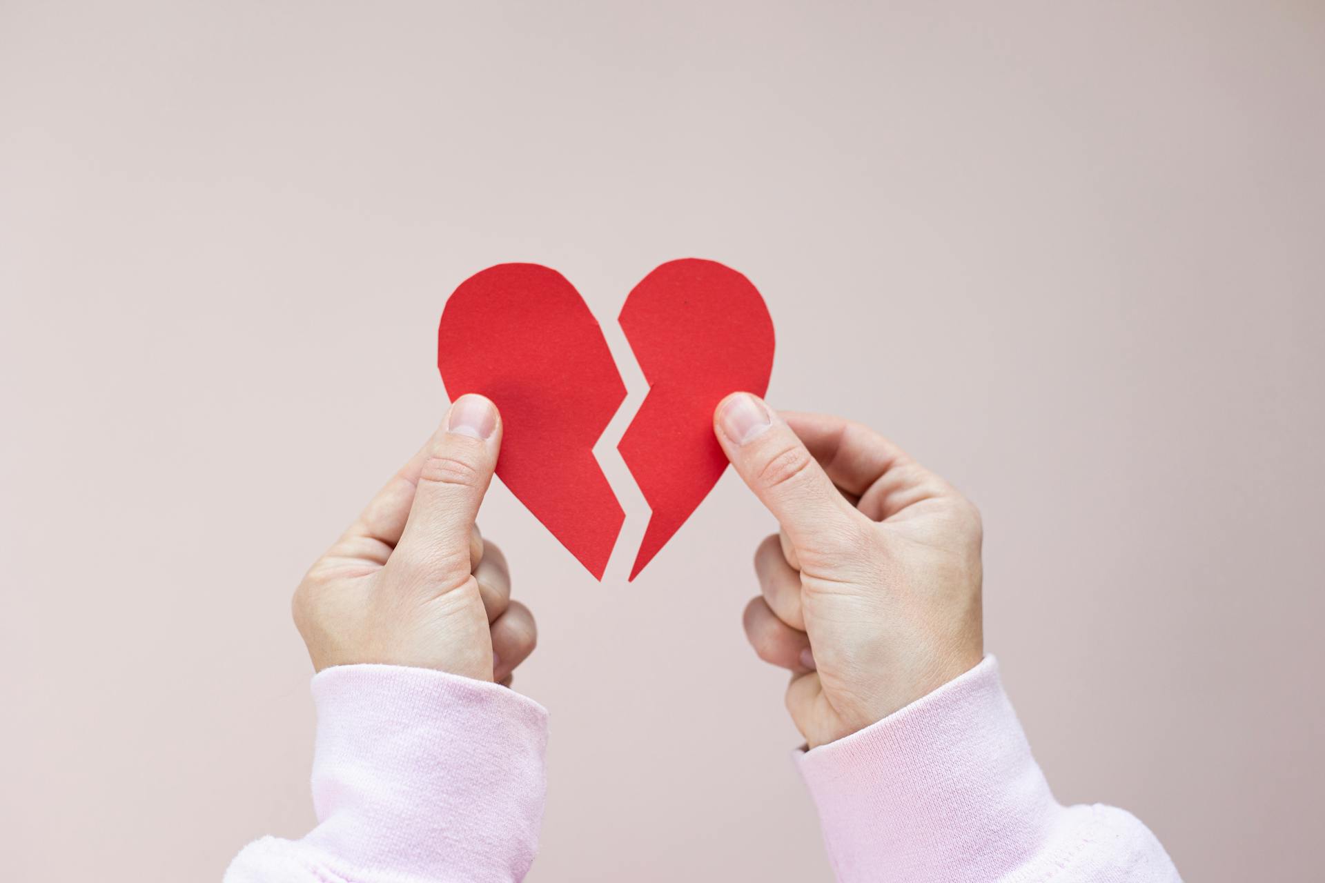 Une personne tenant un cœur en papier rouge brisé | Source : Pexels