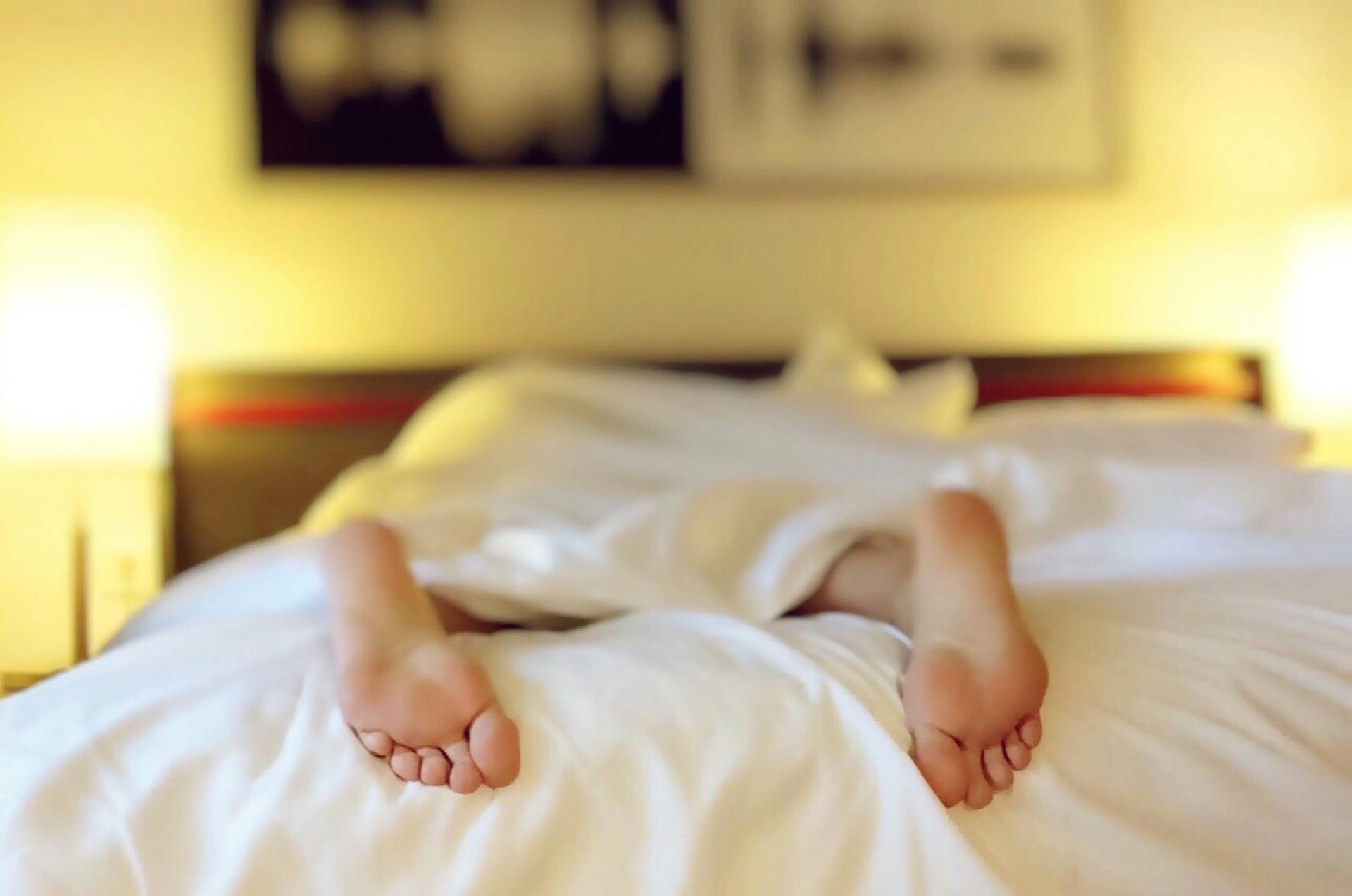 Une personne allongée à plat ventre sur un lit | Source : Pexels