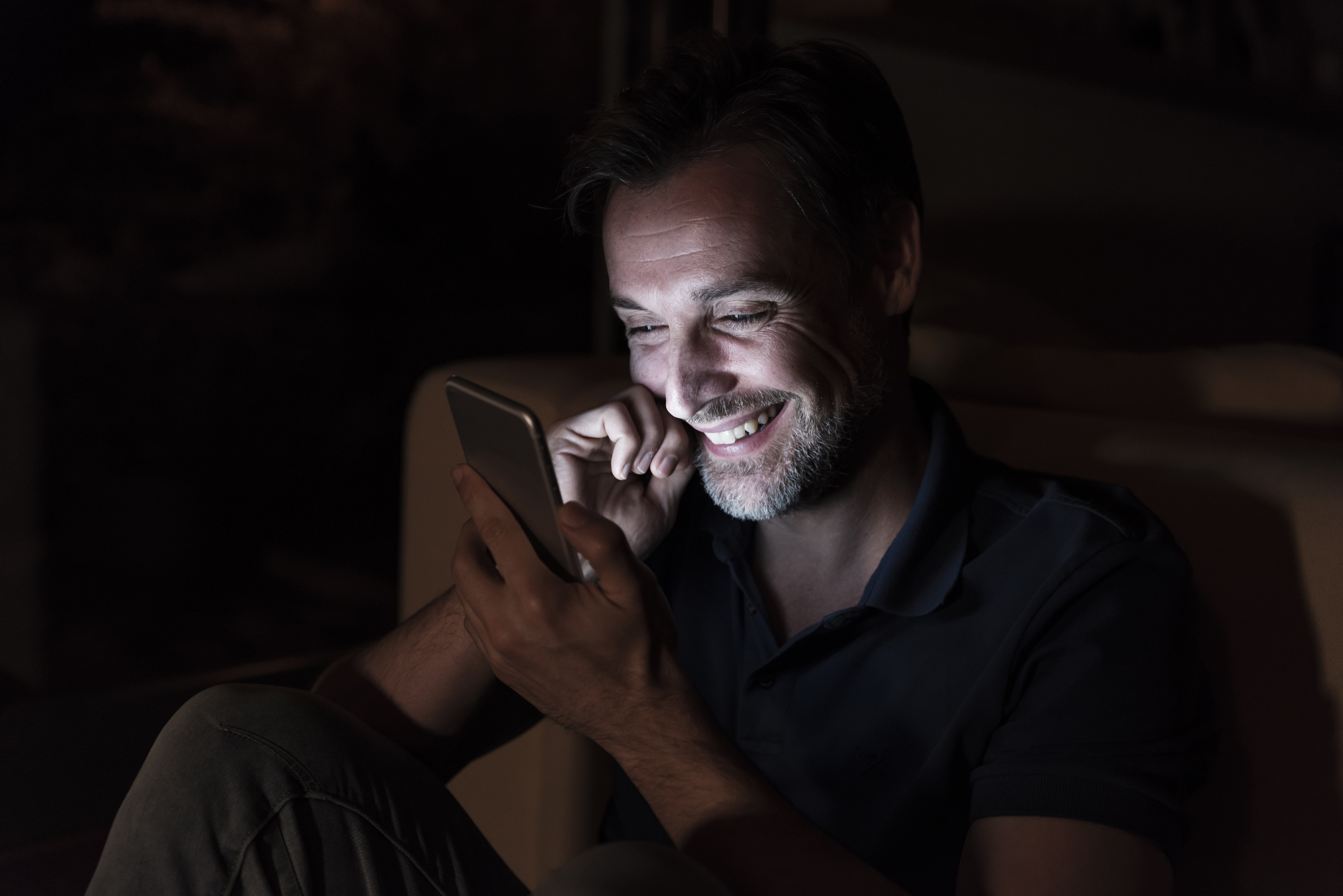 Un homme riant en envoyant un texto | Source : Getty Images