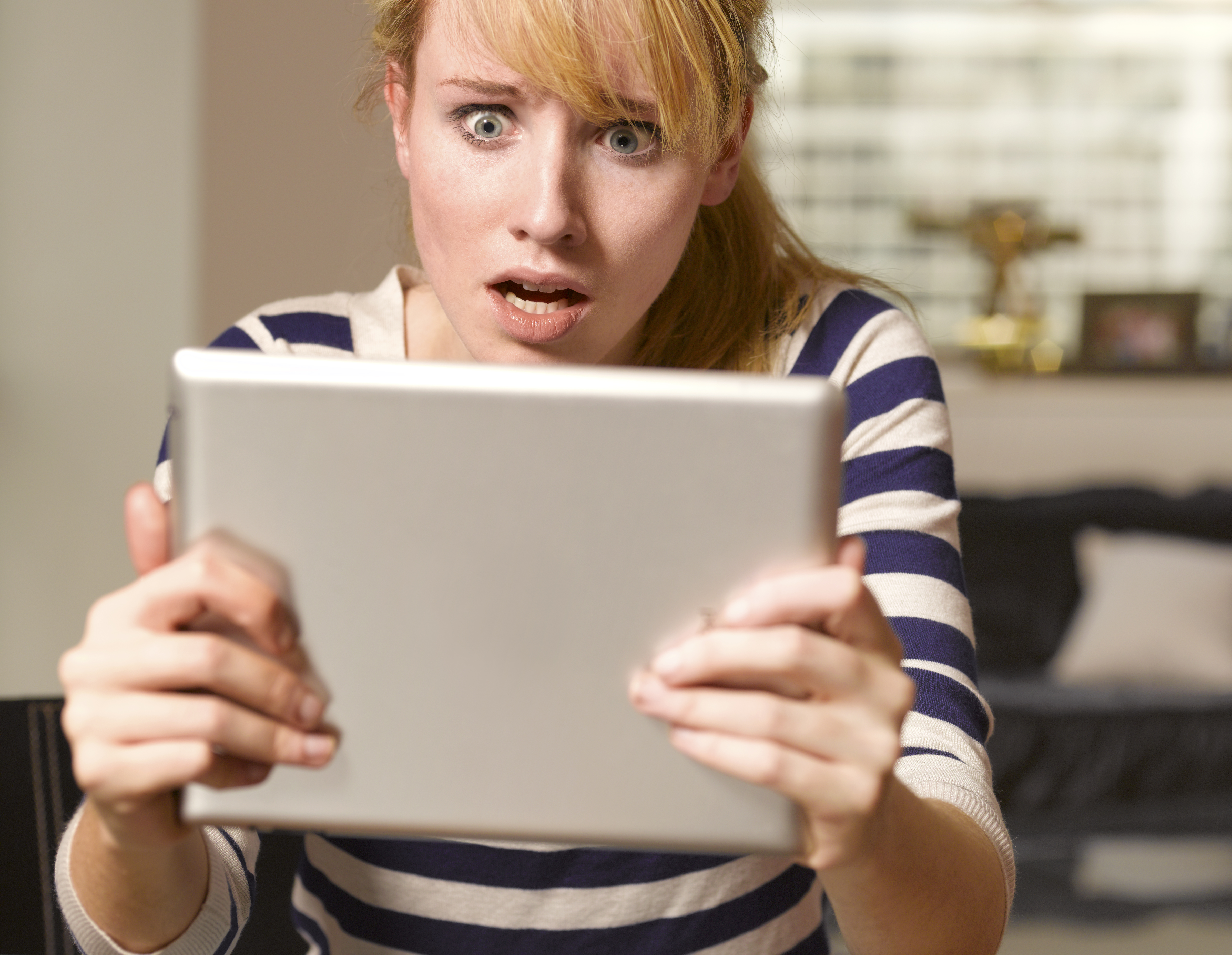 Jeune femme choquée regardant sa tablette | Source : Getty Images