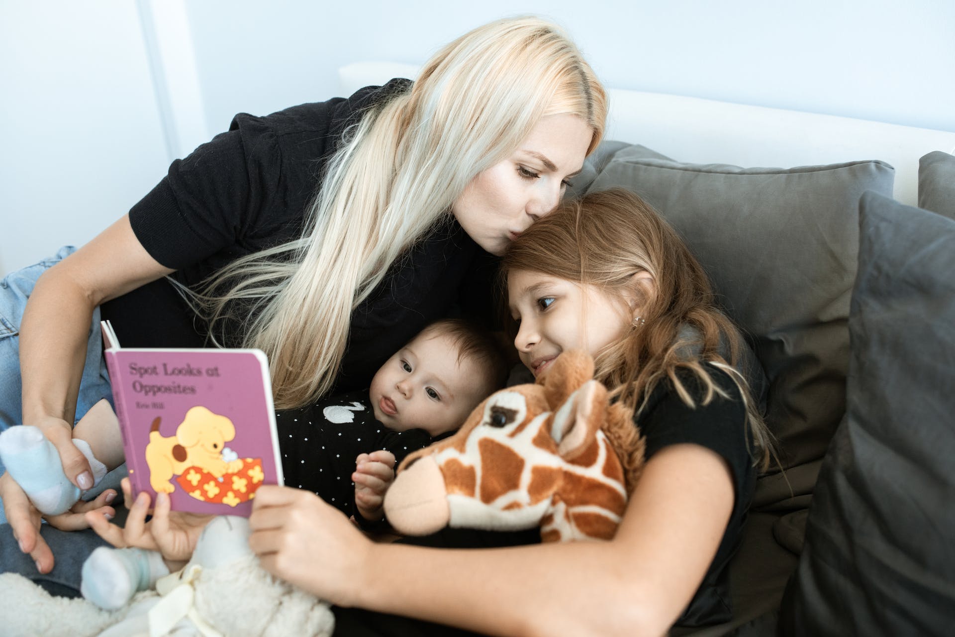 Une femme se lie avec ses deux enfants en leur lisant un livre | Source : Pexels