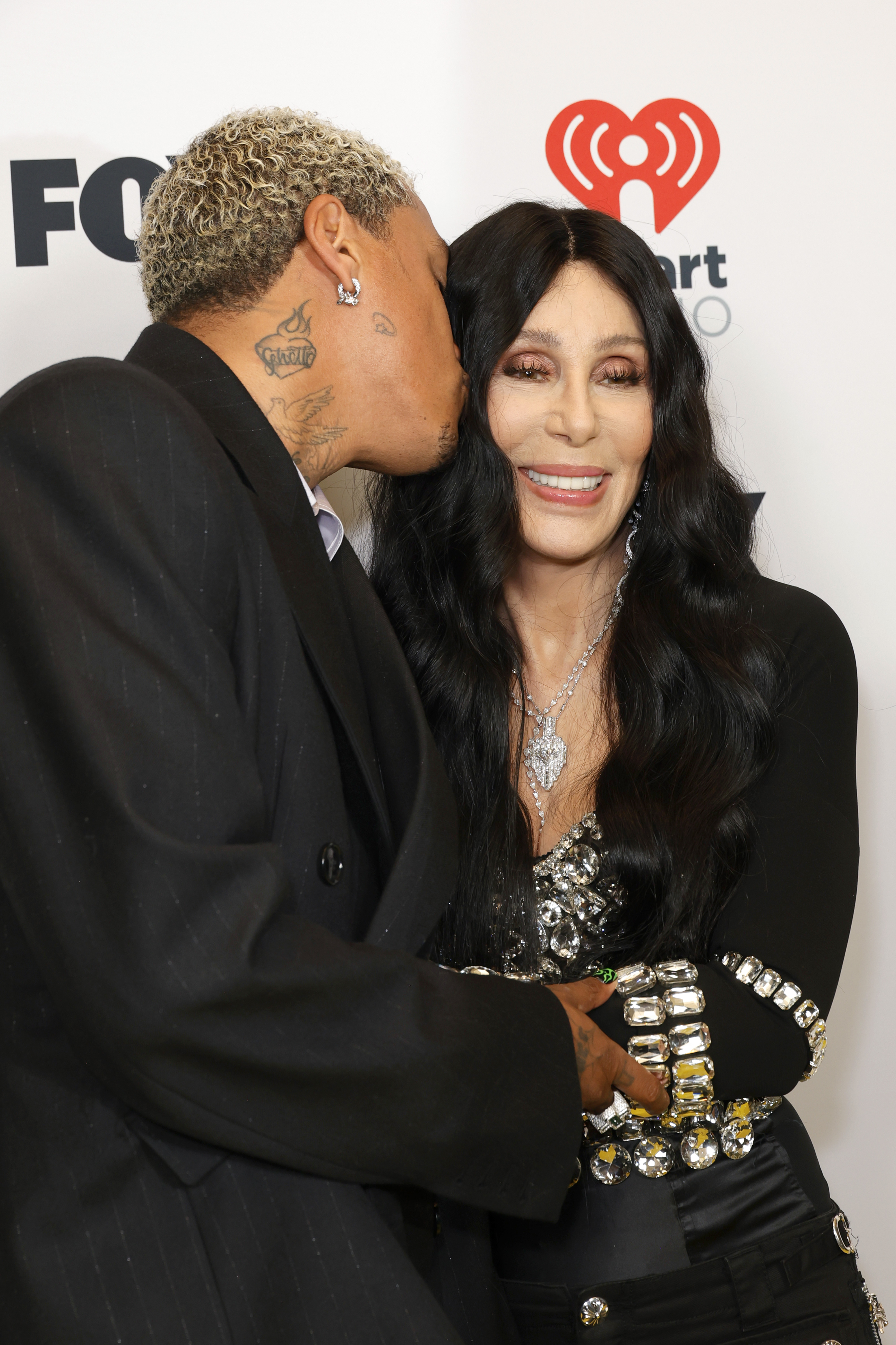 Alexander "AE" Edwards embrasse Cher sur la joue lors des 2024 iHeartRadio Music Awards le 1er avril 2024 à Hollywood, en Californie. | Source : Getty Images