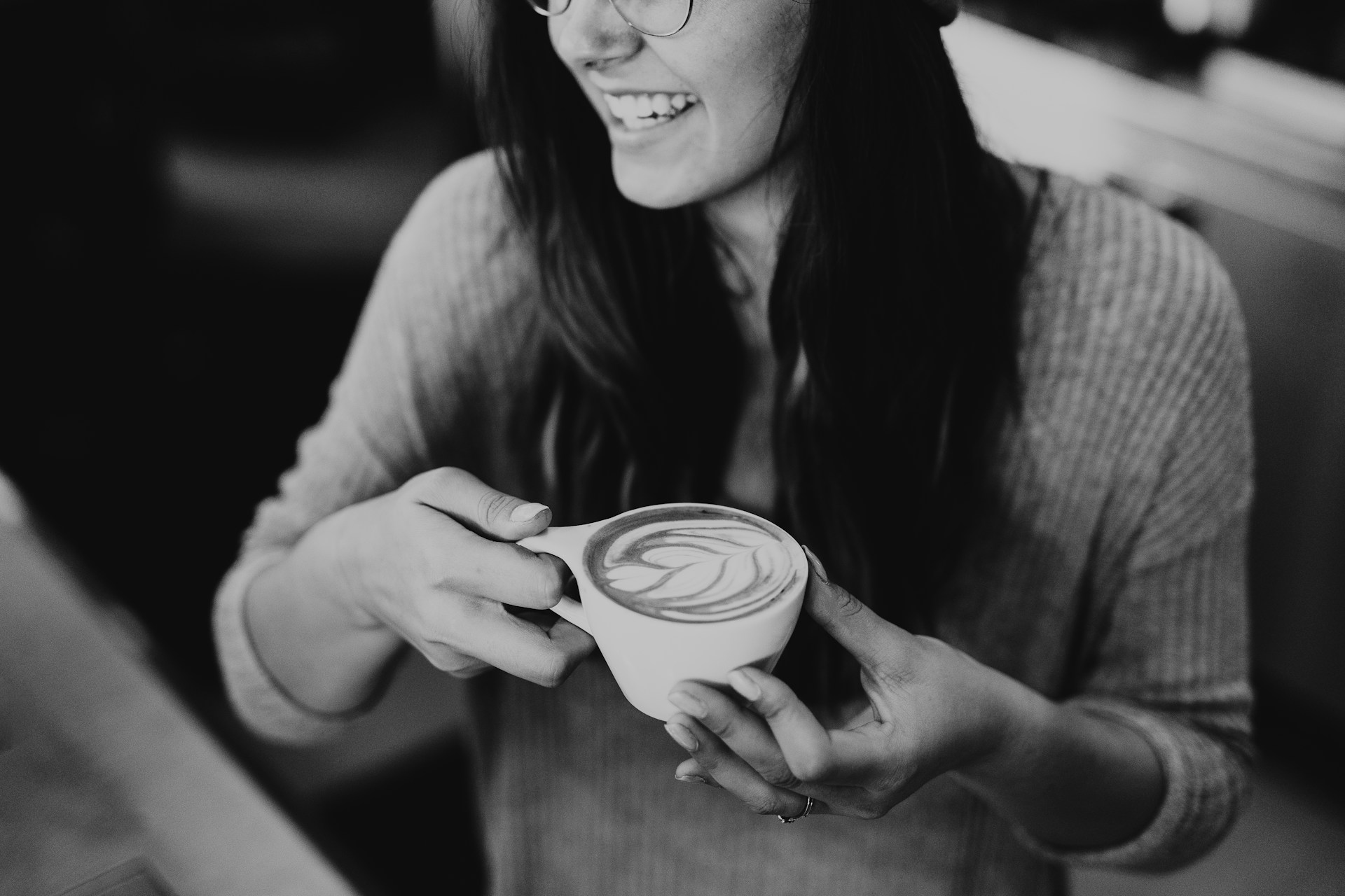 Une femme qui rit en tenant une tasse de café | Source : Unsplash