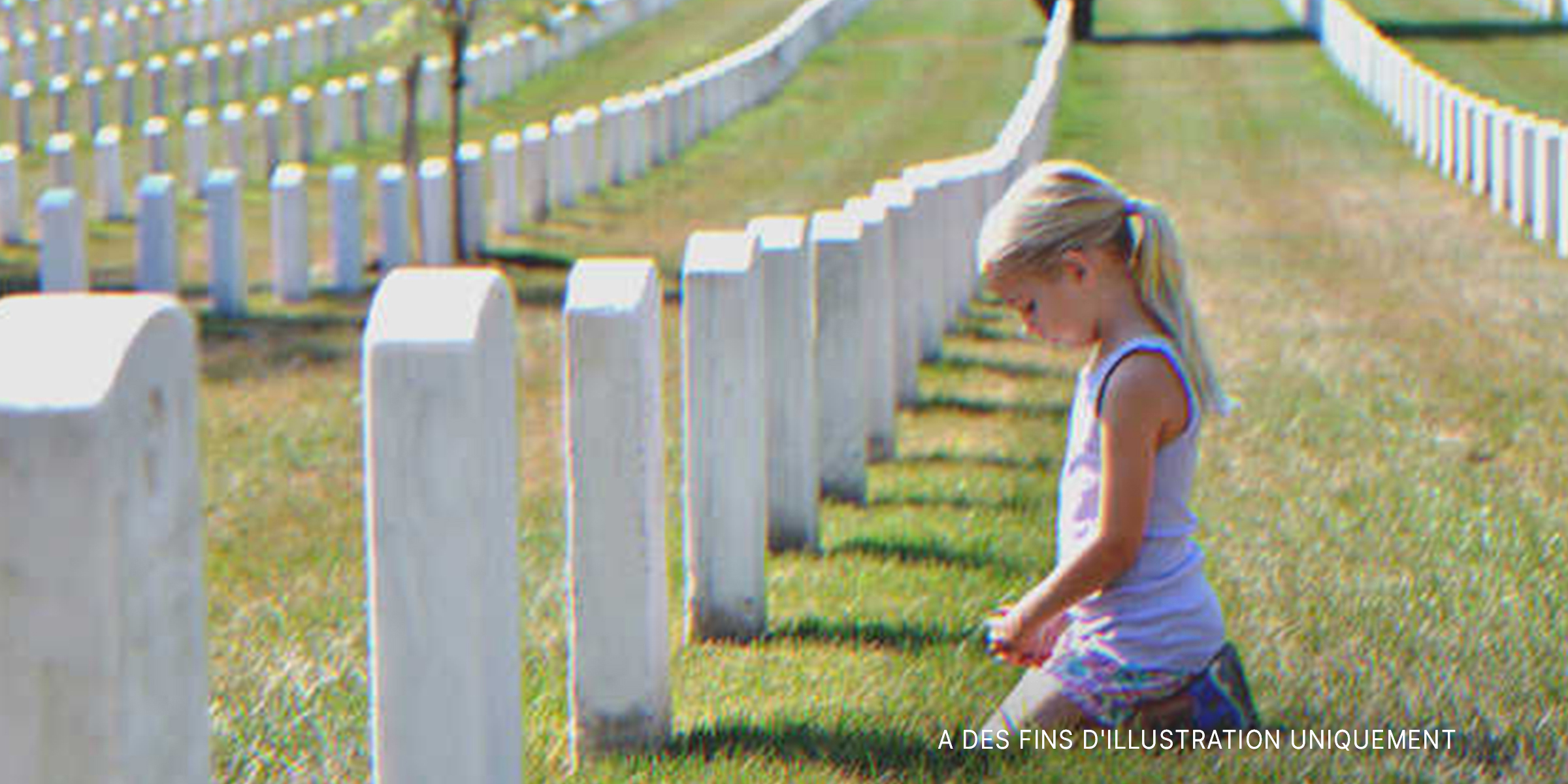 Une petite fille assise devant une pierre tombale | Source : Shutterstock.com