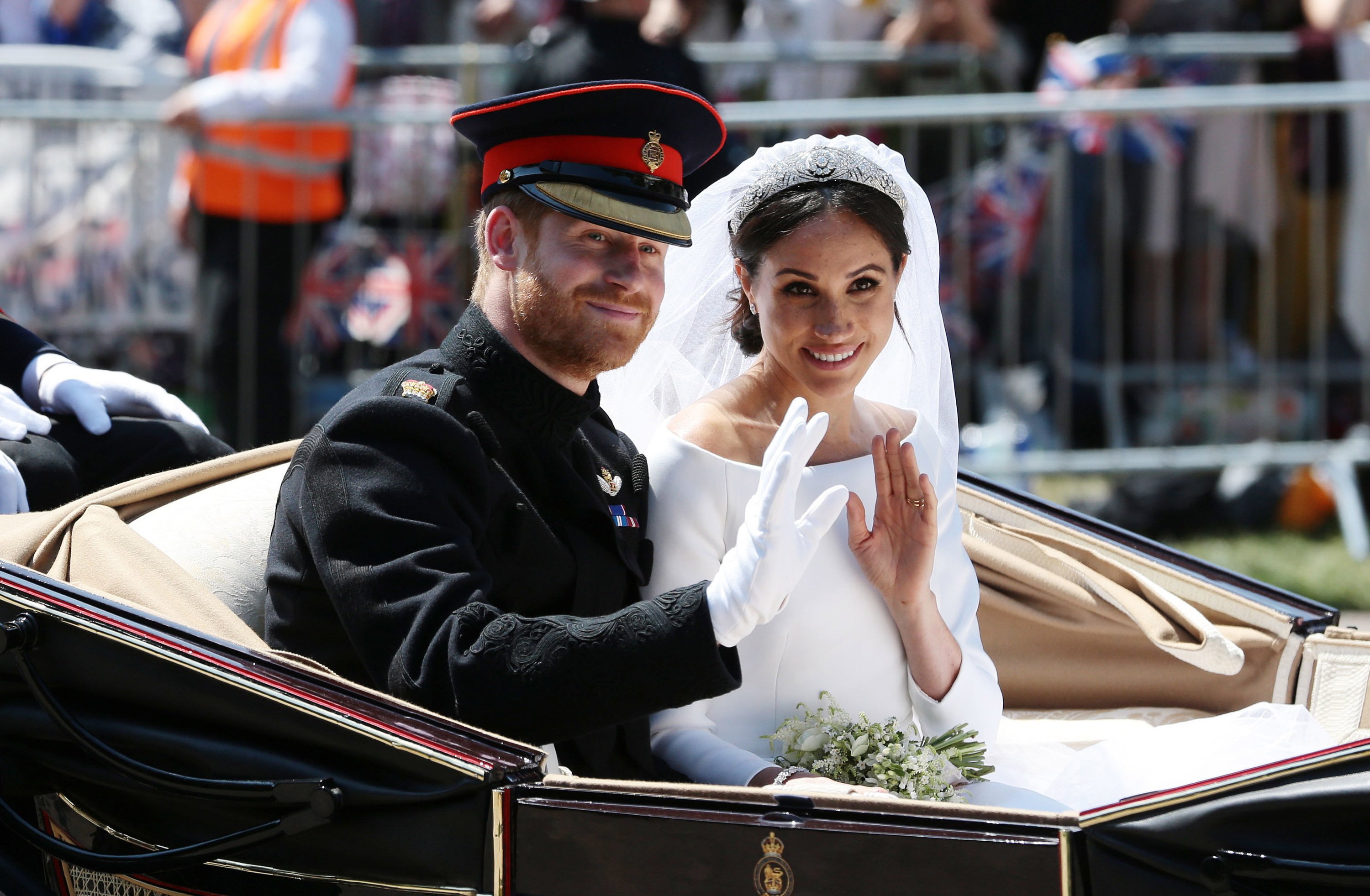 Le prince Harry, duc de Sussex, et Meghan, duchesse de Sussex, saluent depuis le carrosse Ascot Landau lors de leur procession en calèche sur Castle Hill à l'extérieur du château de Windsor, le 19 mai 2018, après leur cérémonie de mariage. | Source : Getty Images