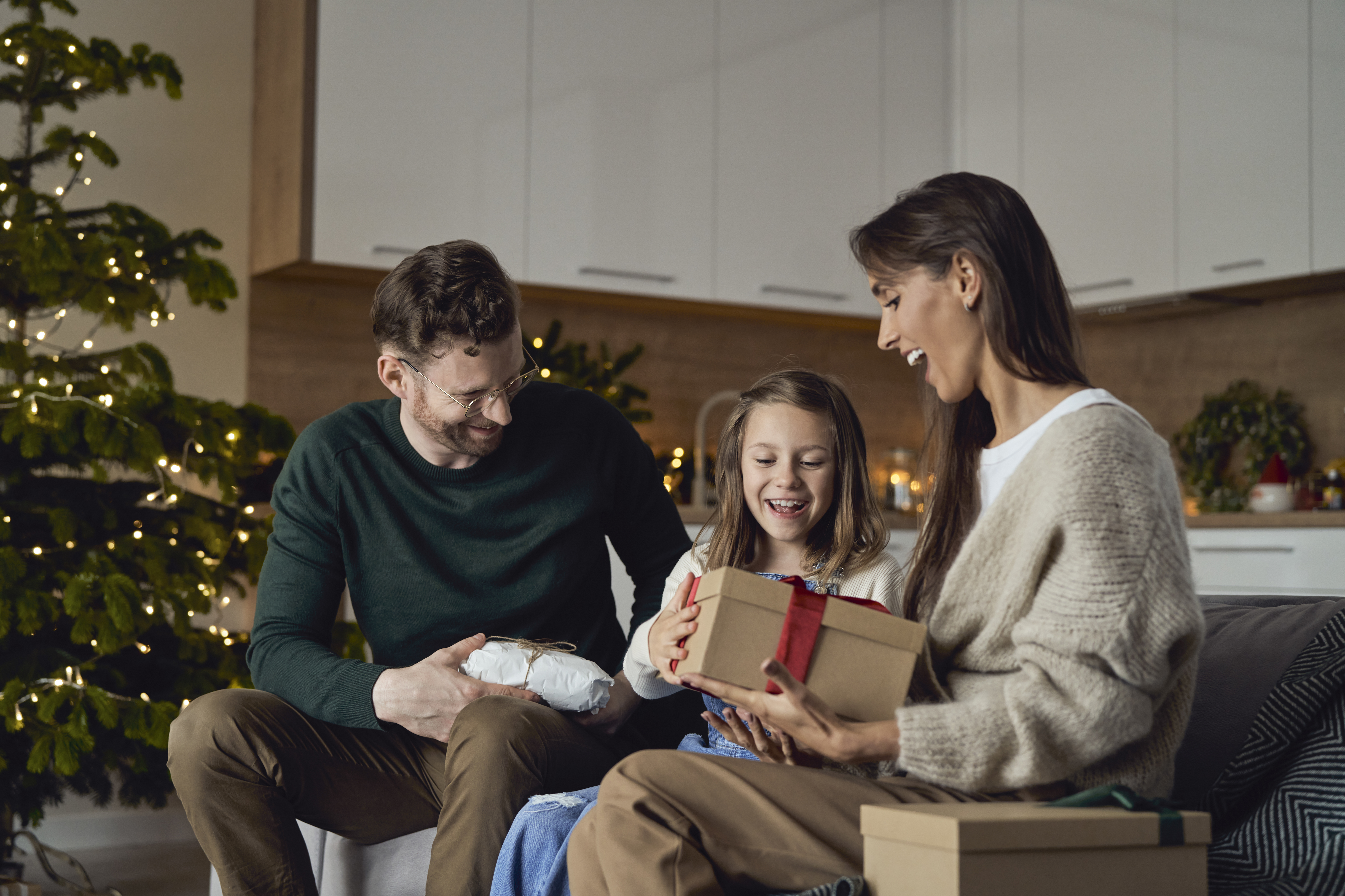 Des parents heureux offrent un cadeau à leur fille à Noël | Source : Getty Images