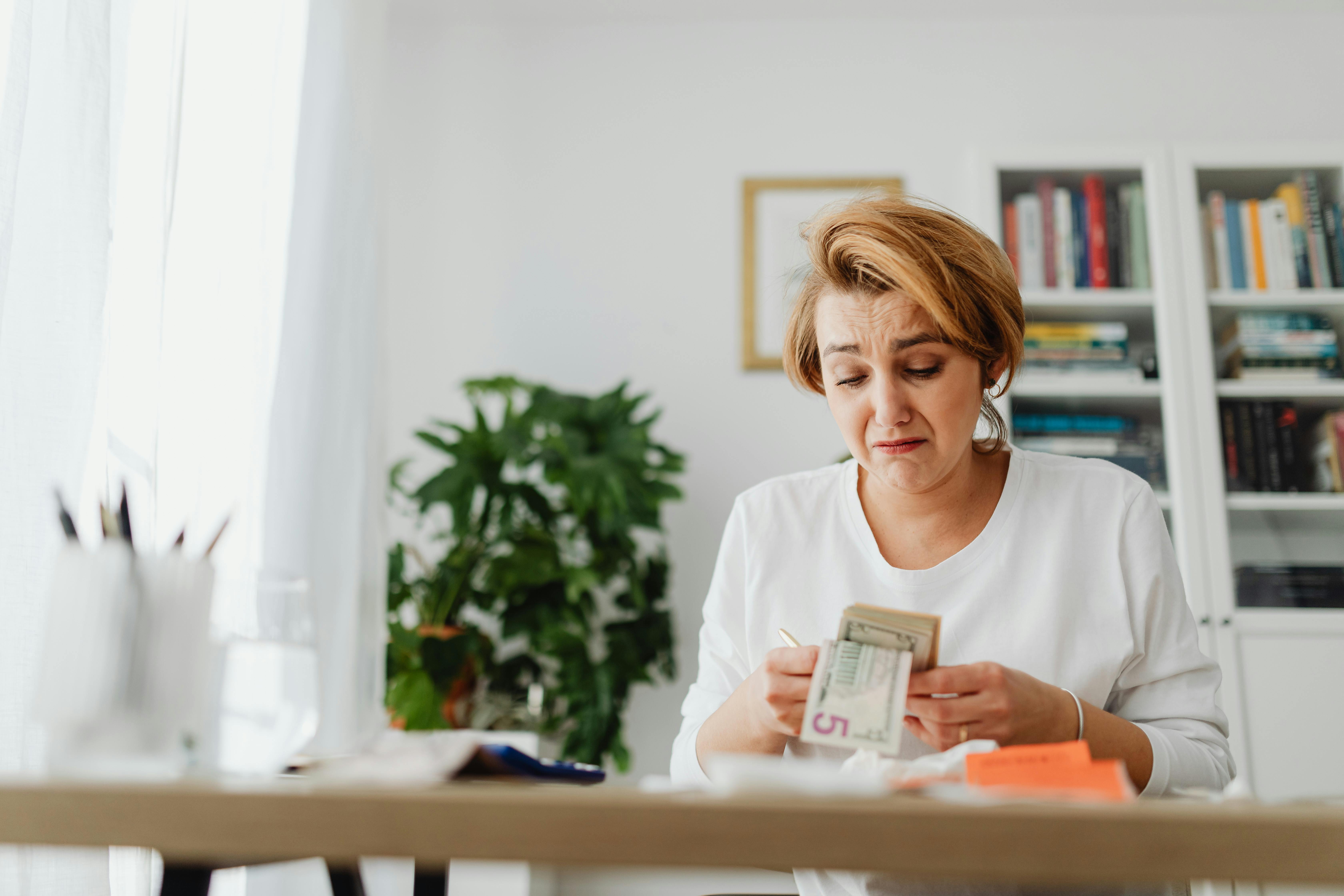 Une femme triste qui compte de l'argent | Source : Pexels