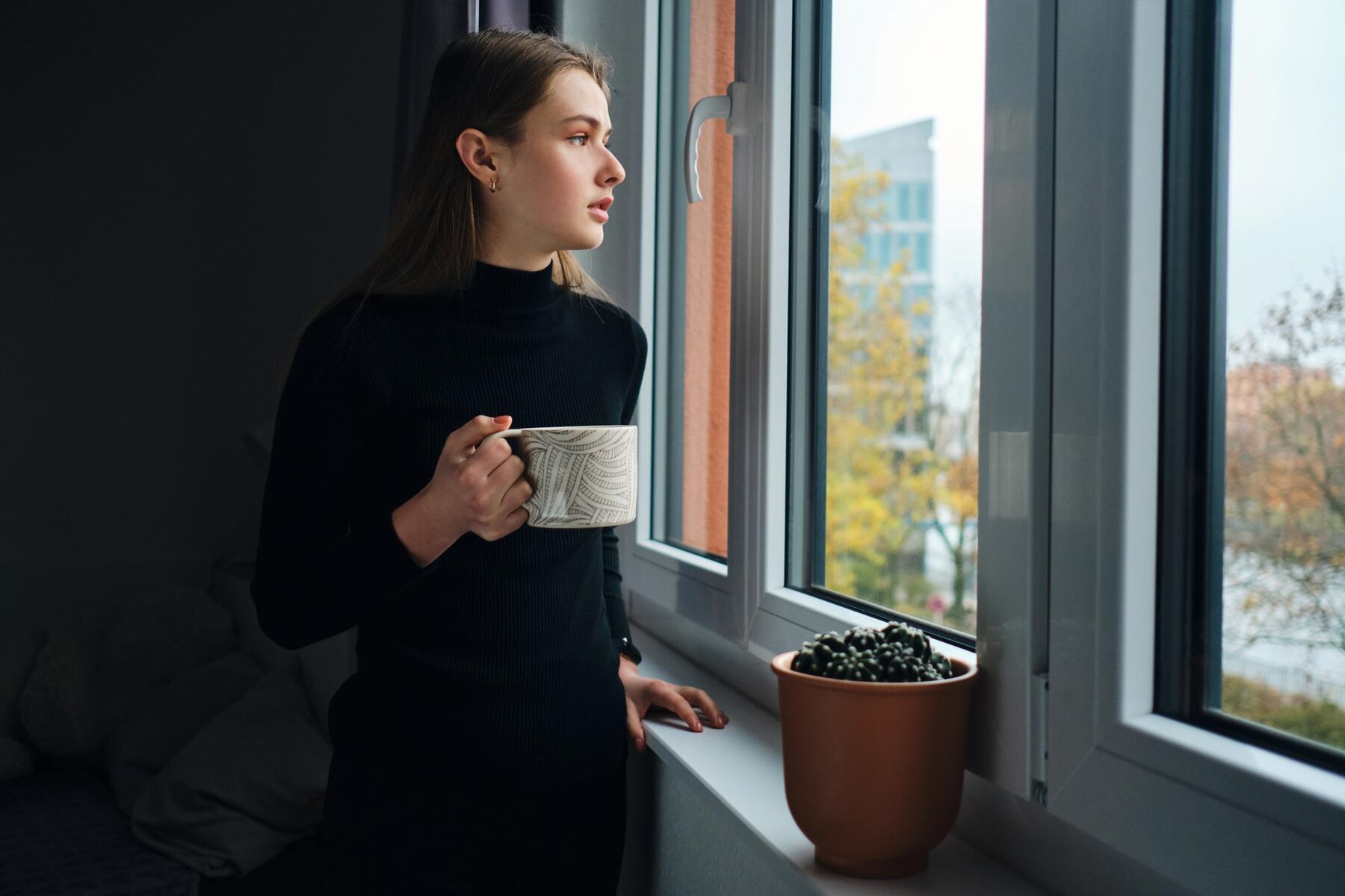 Une femme inquiète qui regarde par la fenêtre | Source : Freepik