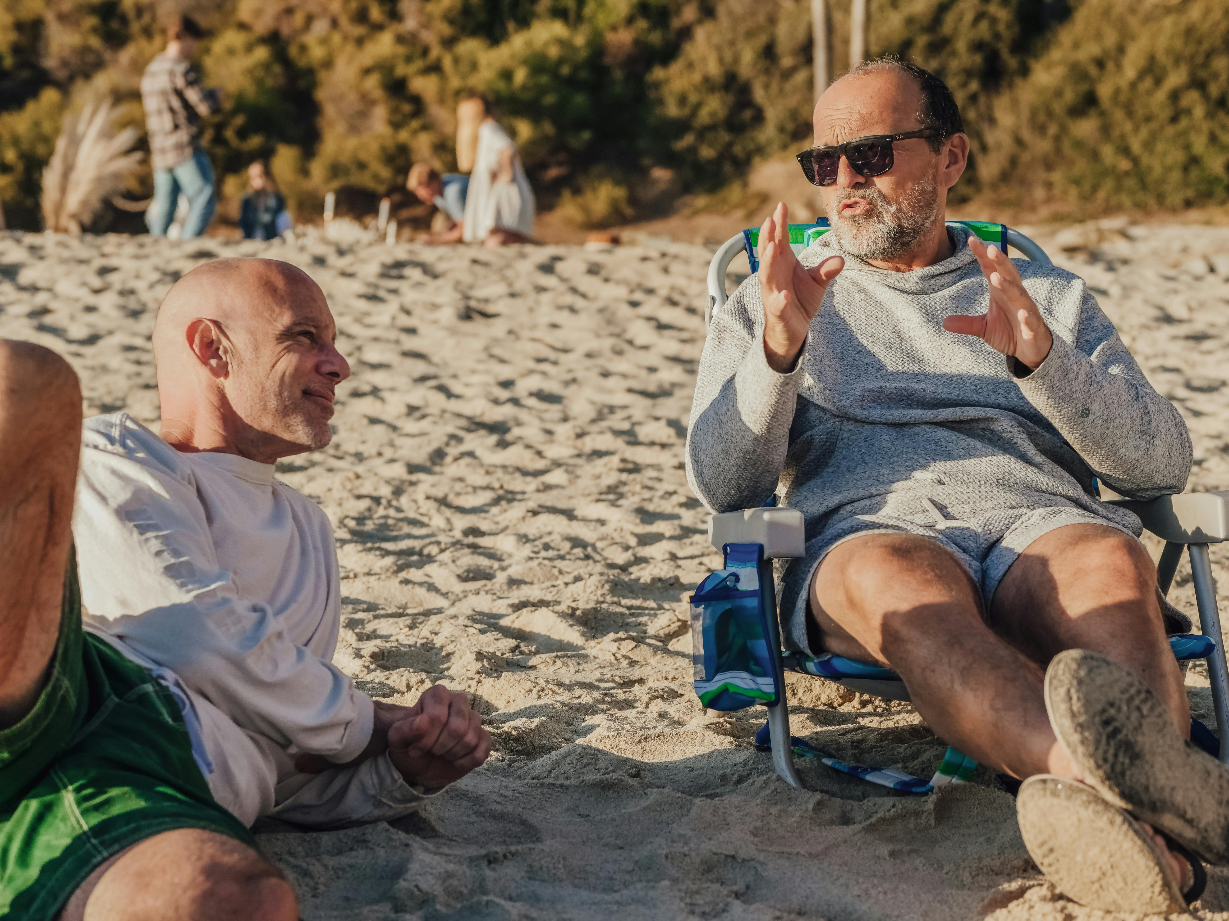 Un homme d'âge moyen se vantant de quelque chose auprès d'un autre homme à la plage | Source : Pexels