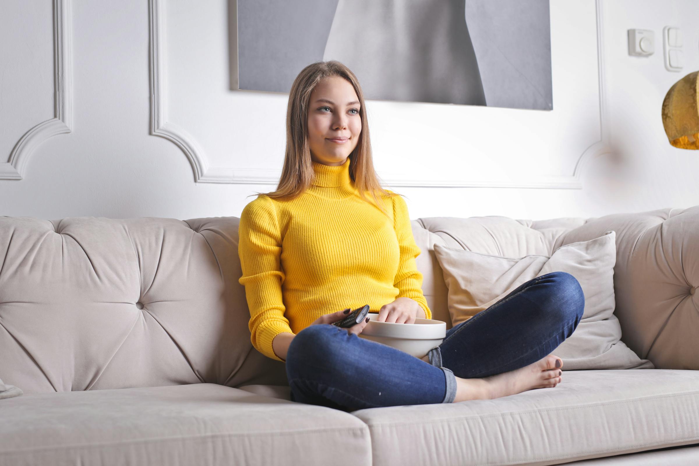 Une femme assise sur un canapé avec du pop-corn | Source : Pexels