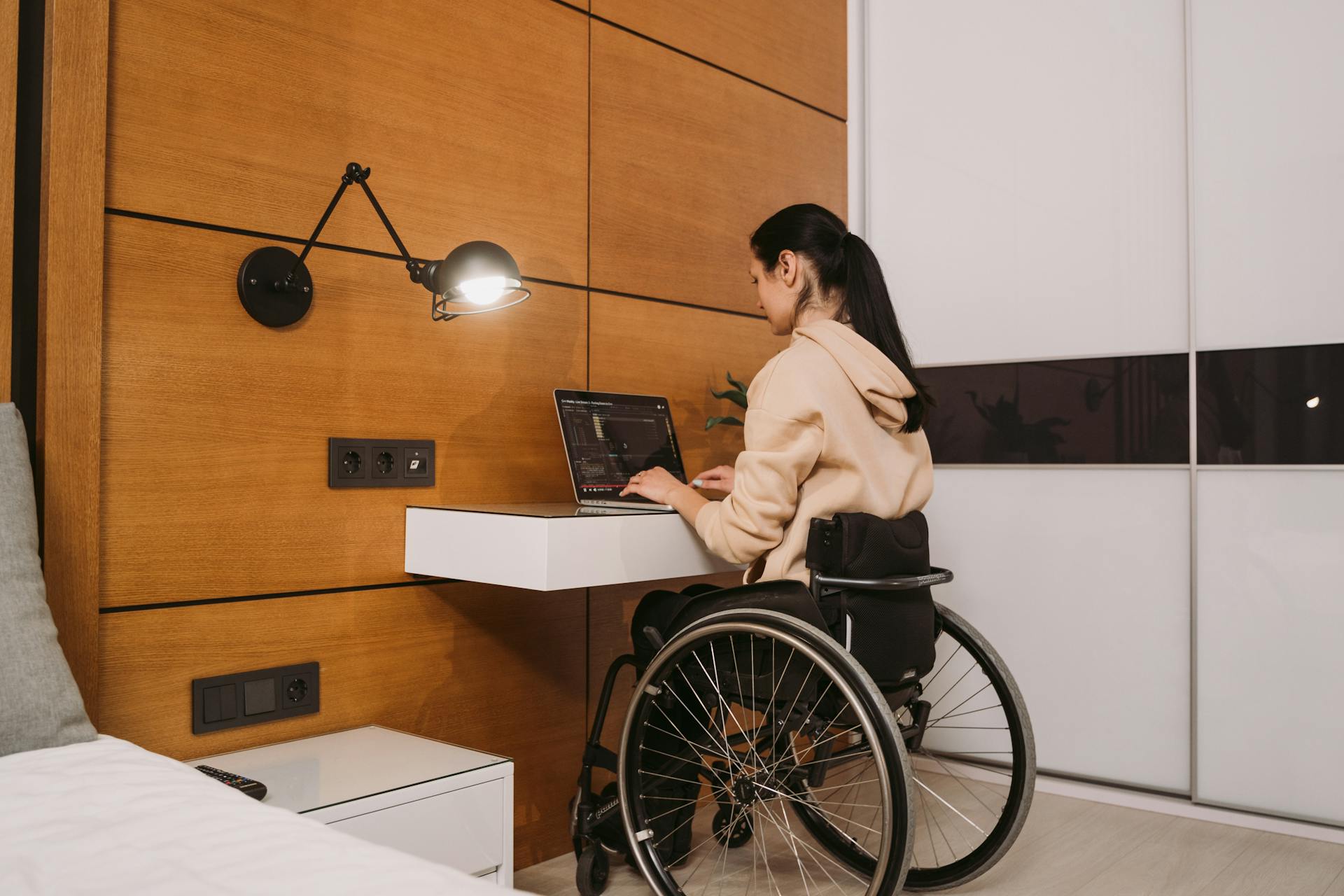 Une femme assise sur son fauteuil roulant et utilisant son ordinateur portable | Source : Pexels