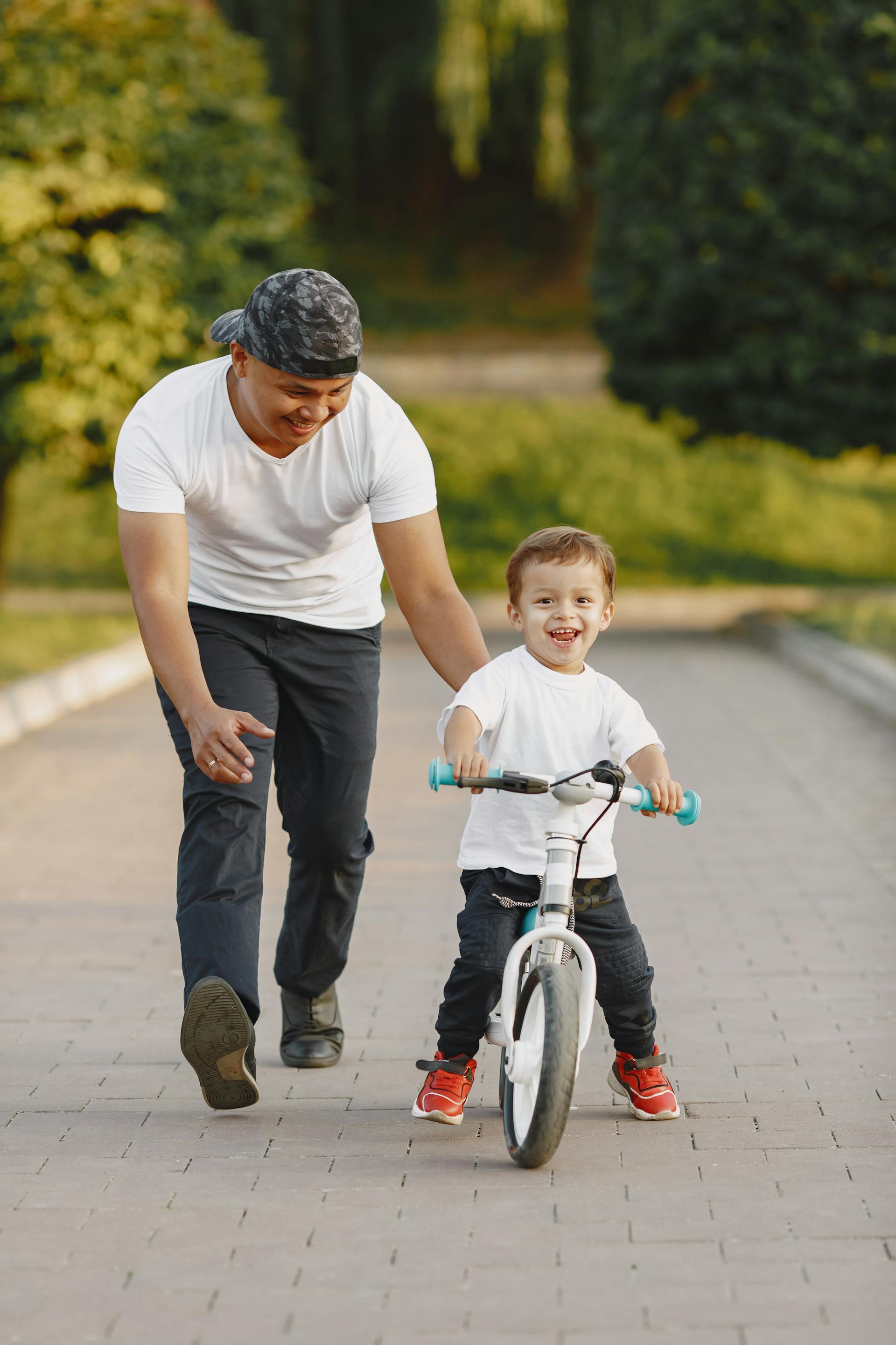 A man guiding his son to ride a bike | Source: Pexels