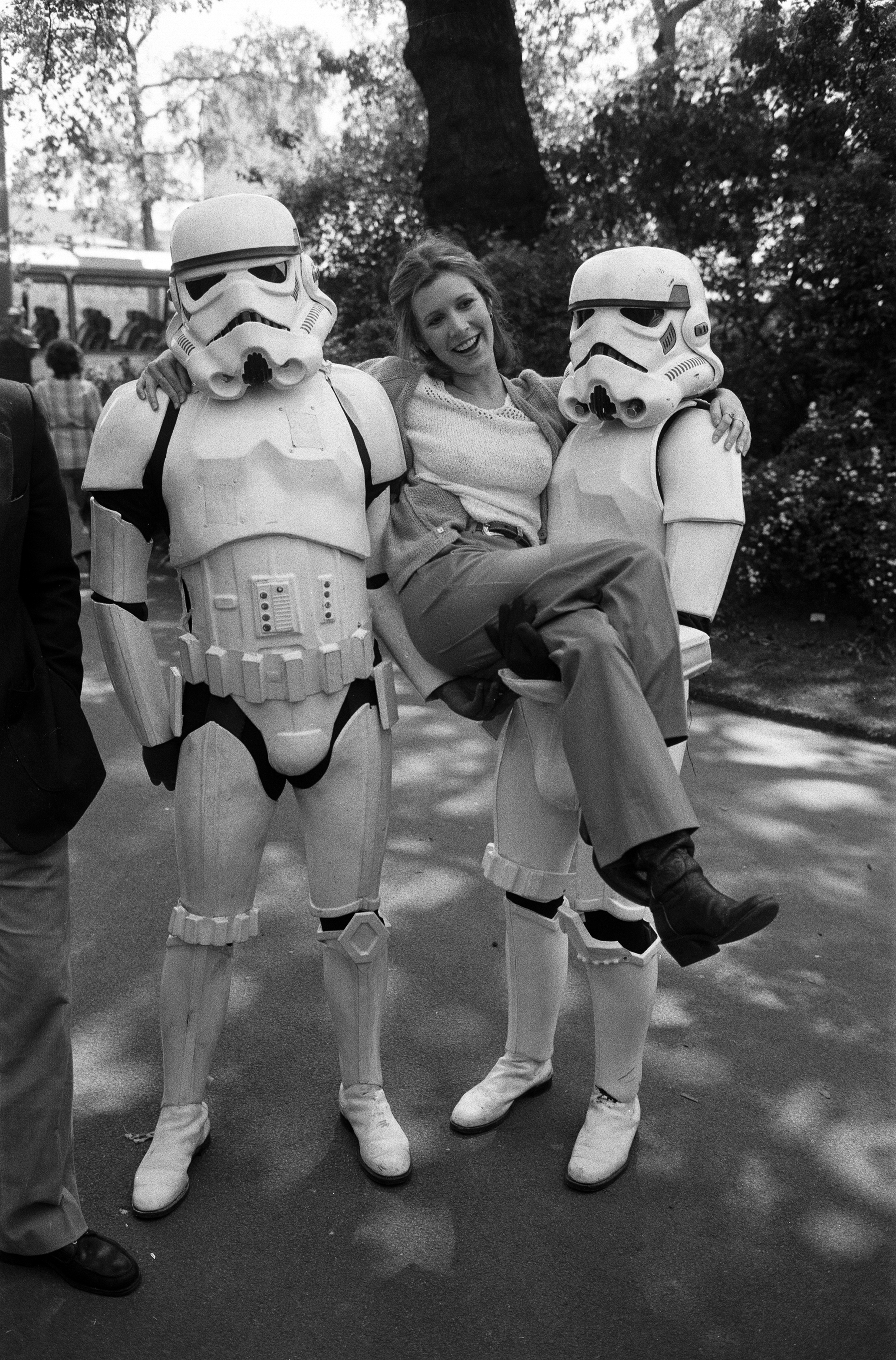 Carrie Fisher et deux Stormtroopers de "Star Wars" la soutenant de chaque côté lors d'un photocall en 1980 | Source : Getty Images