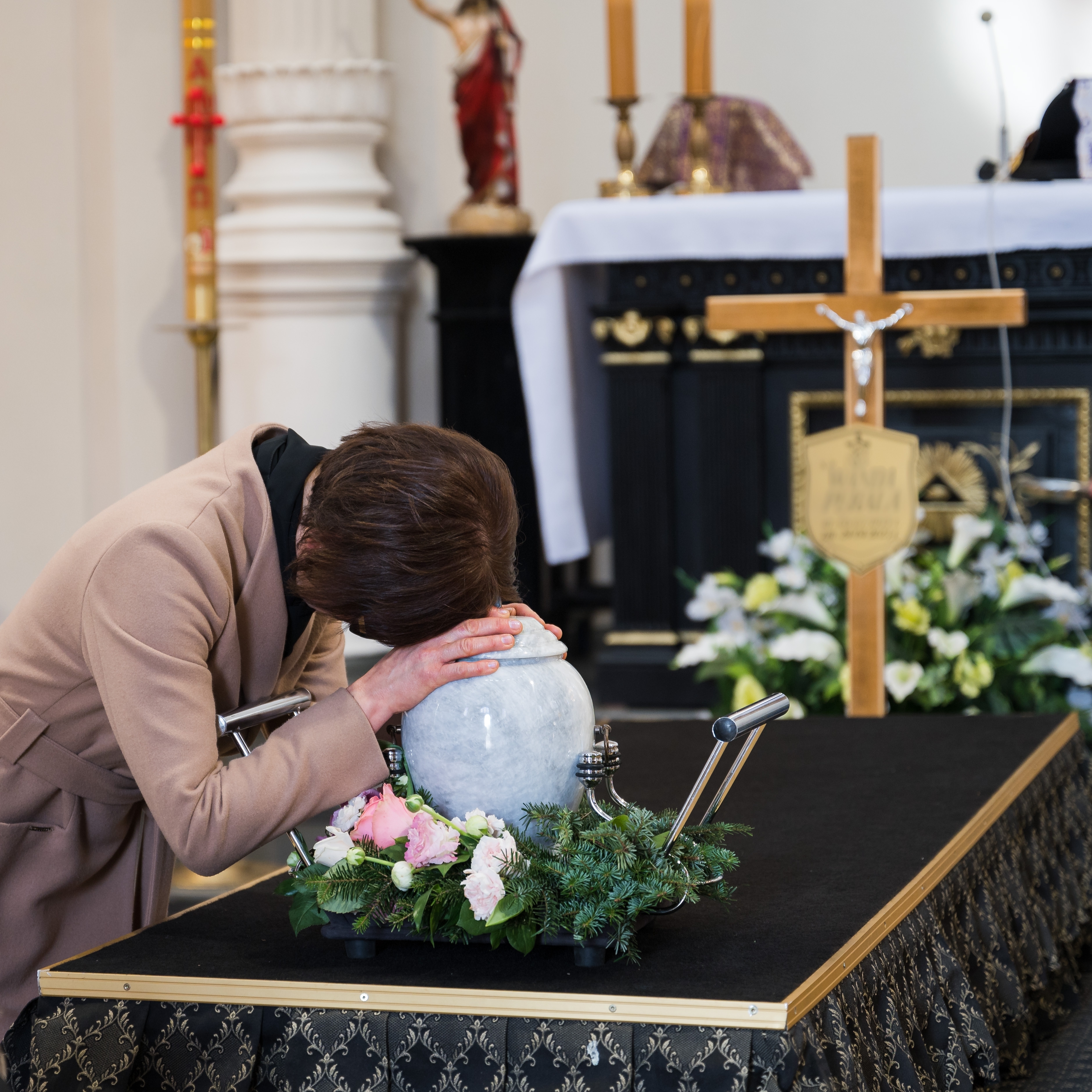 Une femme pleurant sur l'urne d'un être cher lors d'un enterrement | Source : Shutterstock