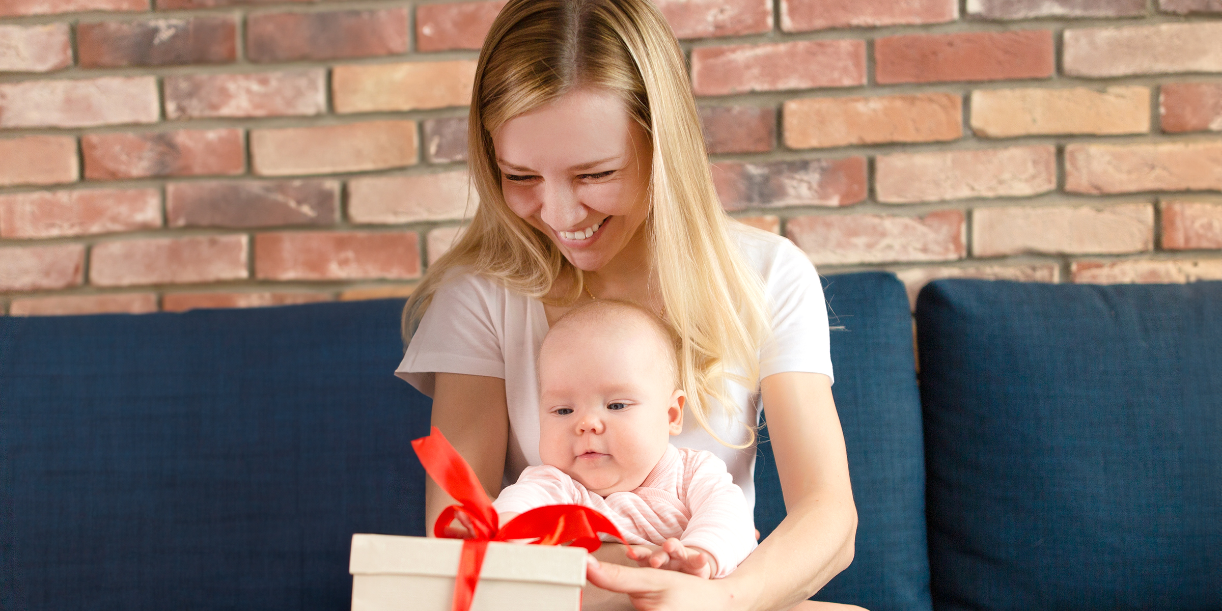 Une femme souriante tenant un bébé et un paquet cadeau | Source : Shutterstock