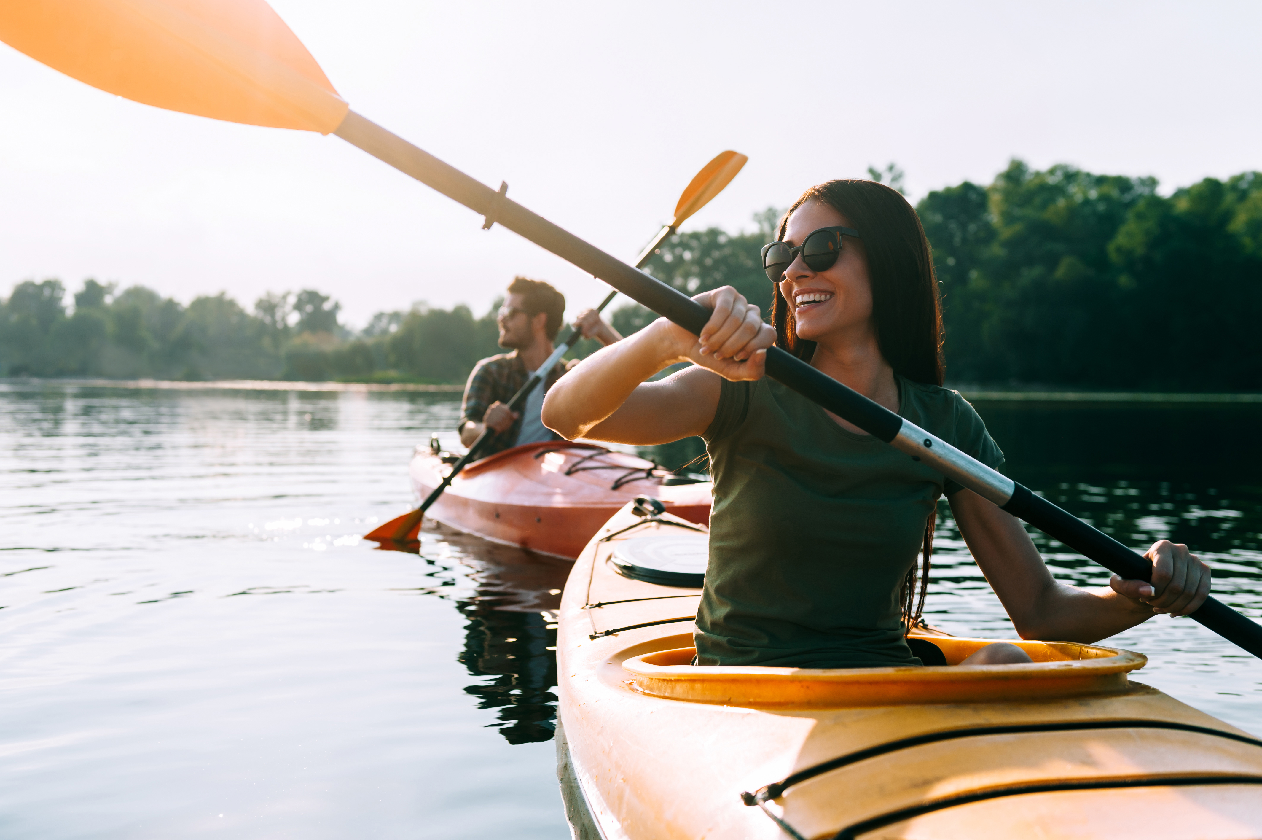 Un jeune couple fait du kayak sur le lac ensemble et sourit | Source : Shutterstock